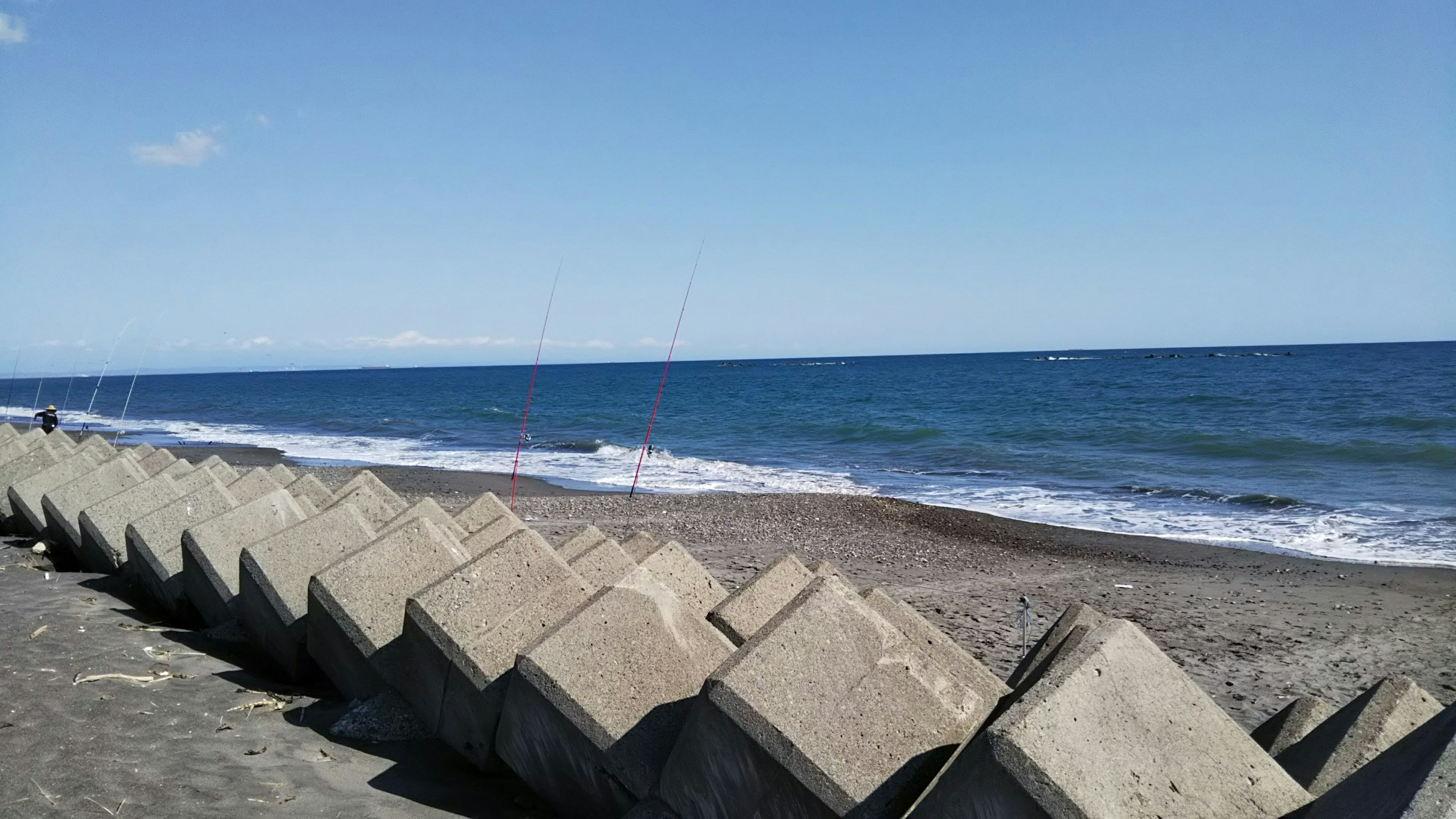 Blocchi di cemento lungo una spiaggia con oceano blu e cielo sereno