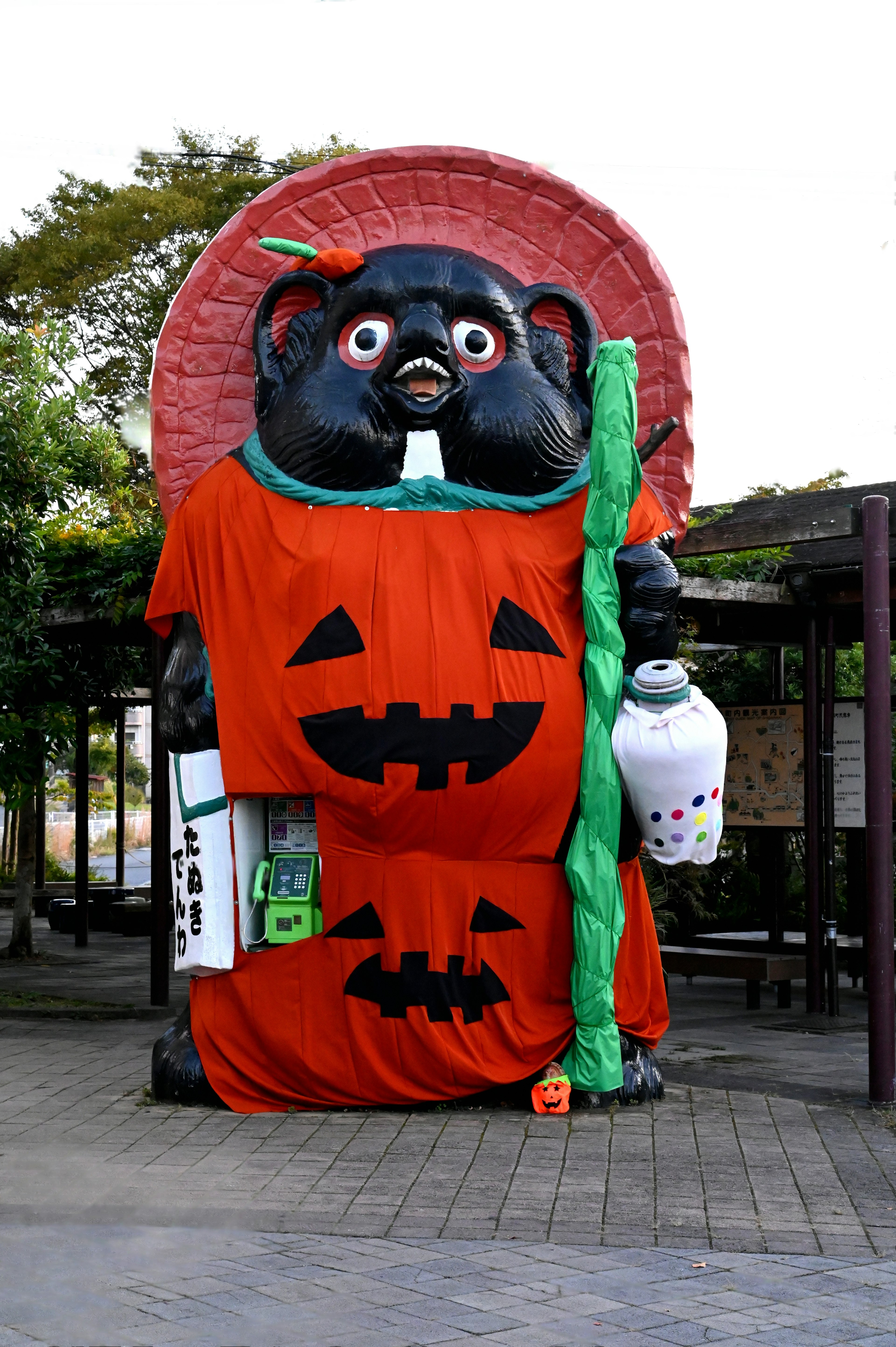 Large tanuki statue dressed in Halloween costume with pumpkin design