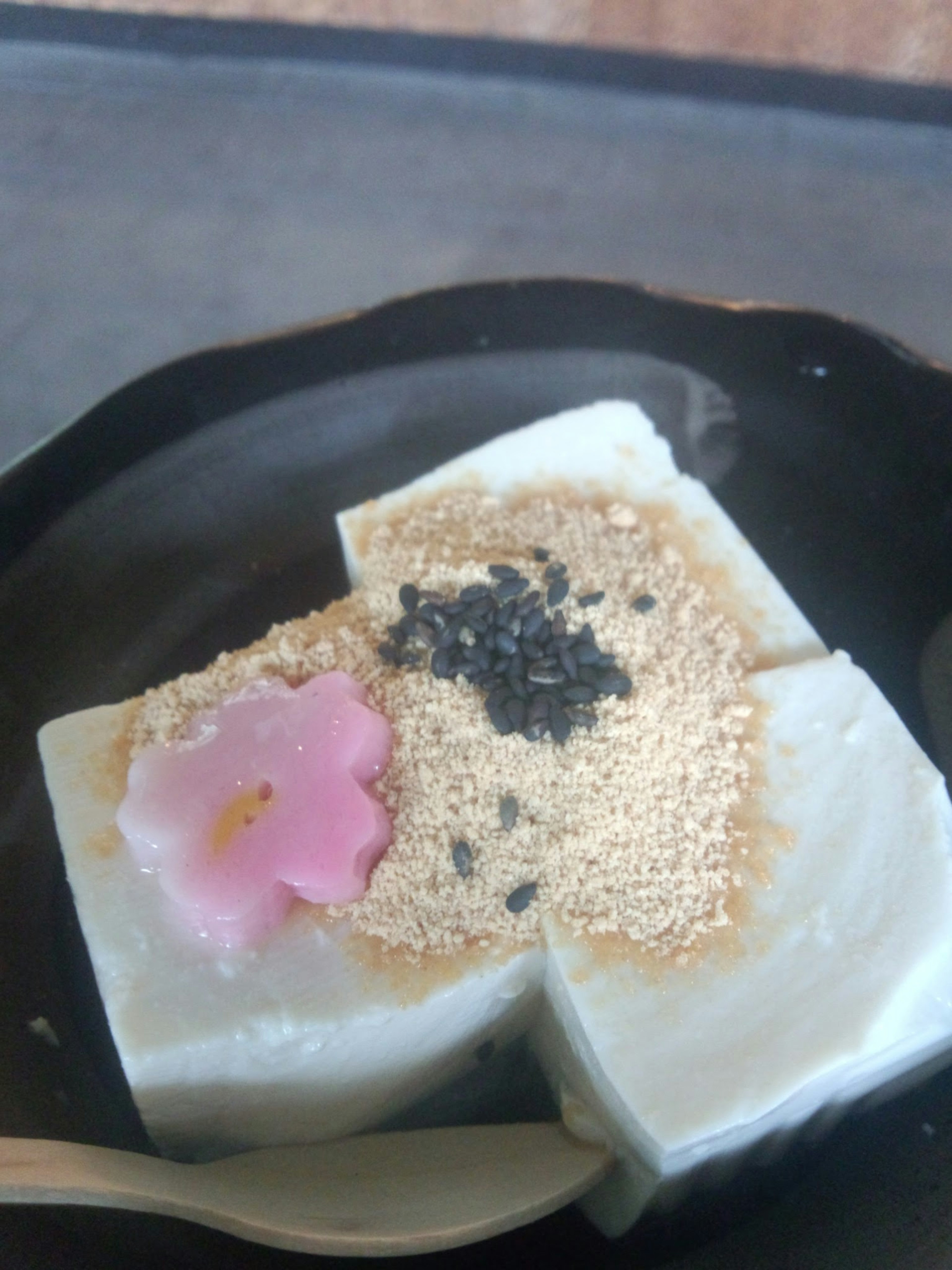 Un joli dessert avec des douceurs japonaises blanches garnies d'une fleur de cerisier et de graines de sésame noir