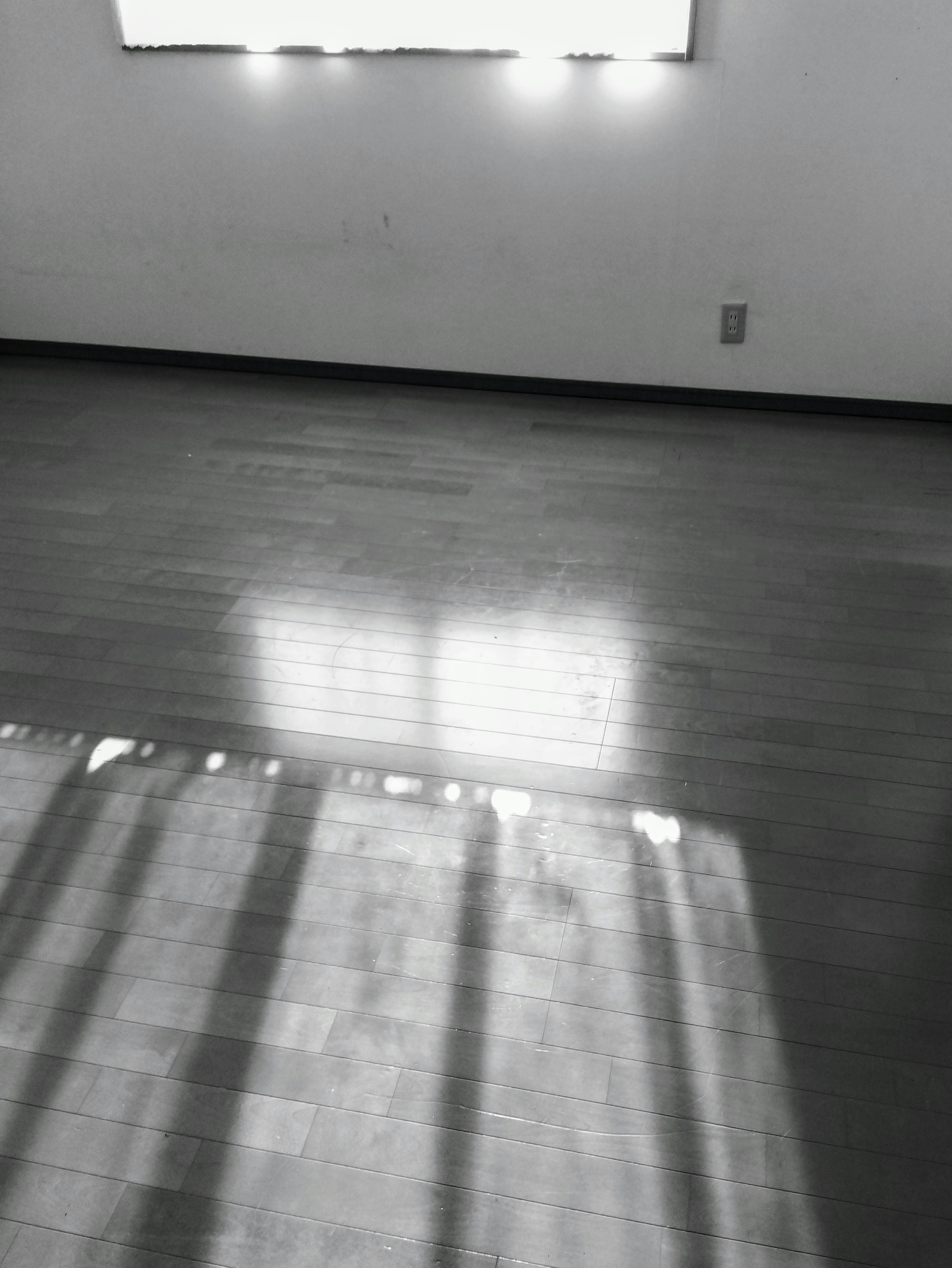 Room with wooden floor reflecting light from bright window