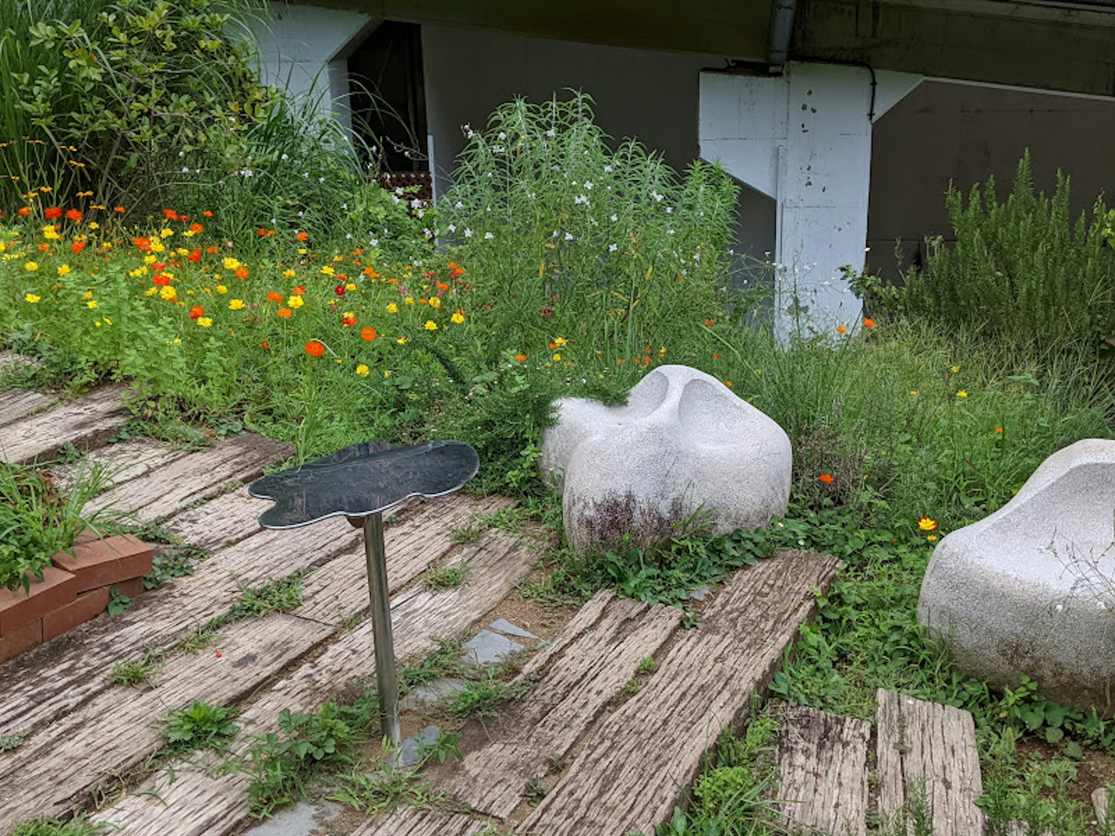 Weiße Steinstühle in einem üppigen Garten mit bunten Blumen