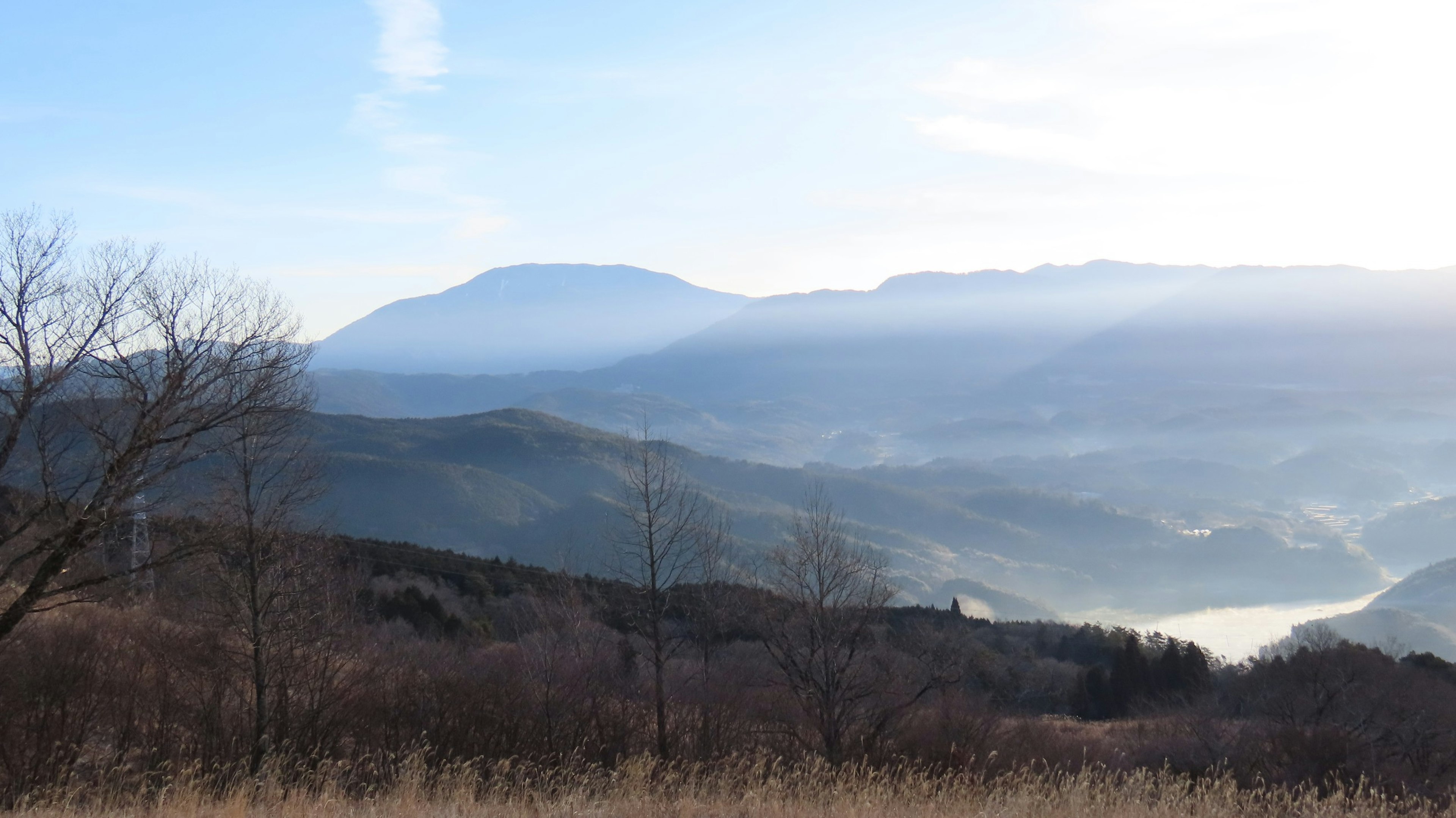 Landschaft mit in Nebel gehüllten Bergen und blauem Himmel