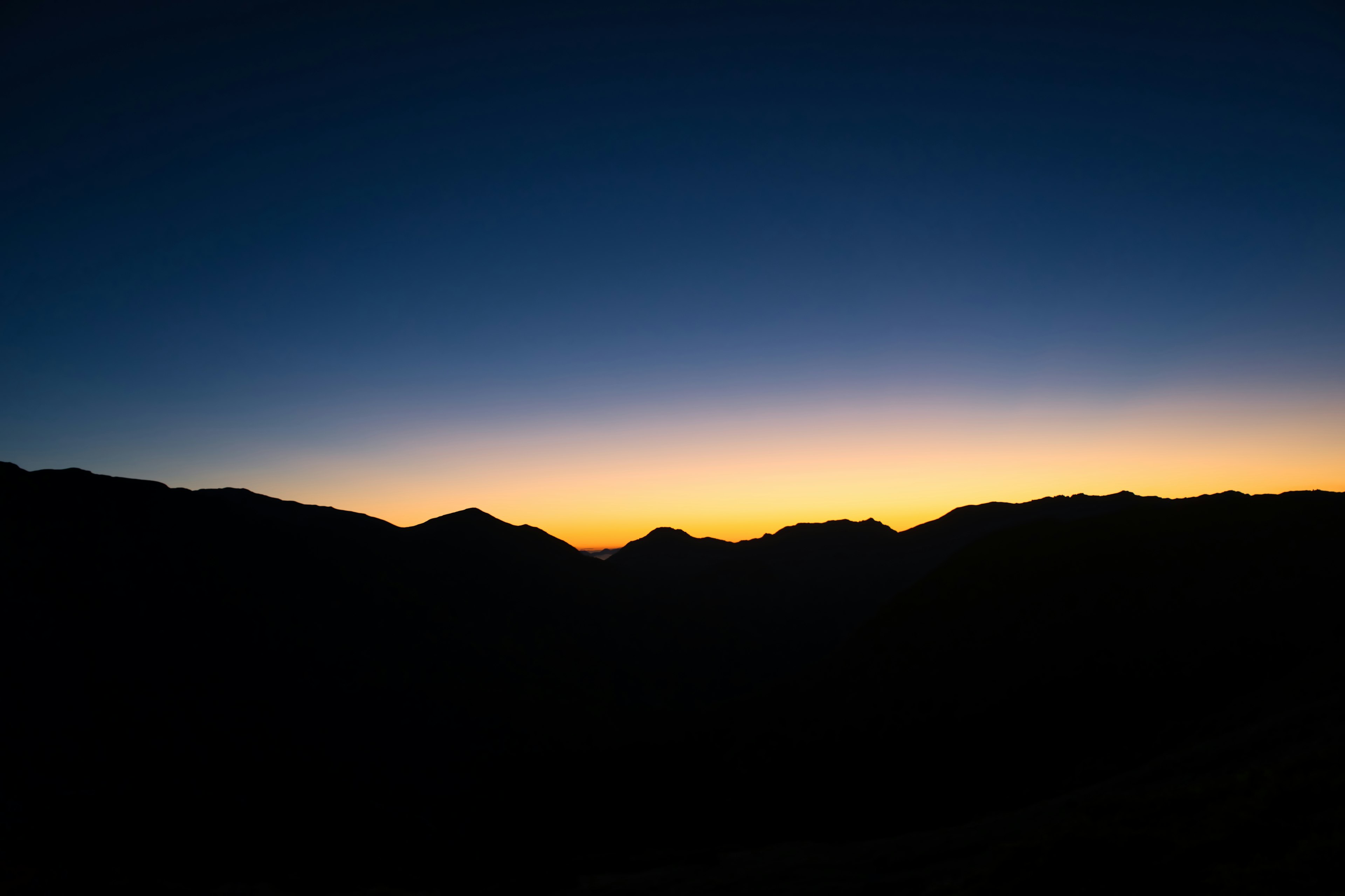 Silhouette di montagne contro un cielo notturno sfumato