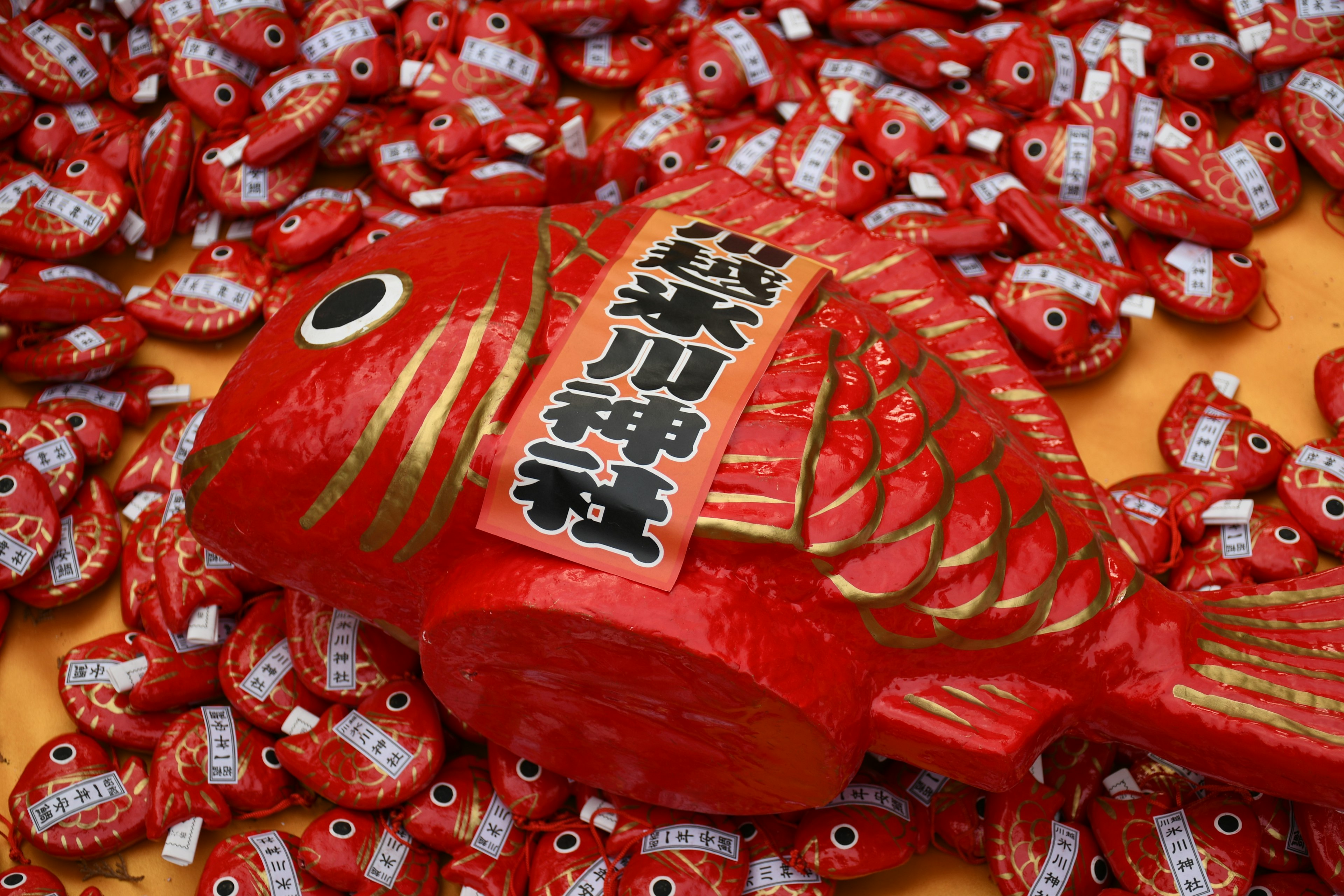 Ikan dekoratif merah dengan karakter Jepang dikelilingi permen ikan kecil