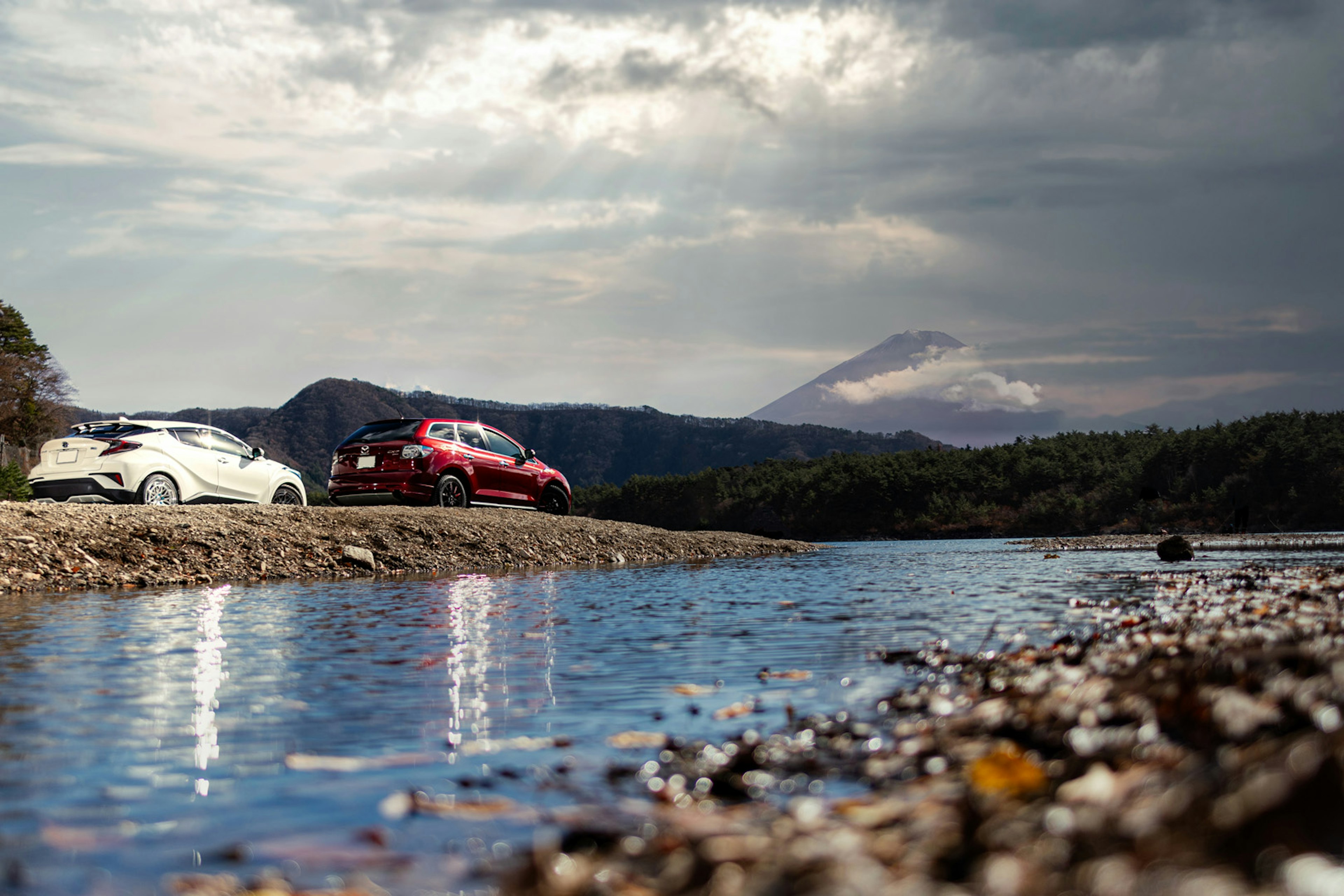 Due auto con il monte Fuji sullo sfondo e una superficie d'acqua calma