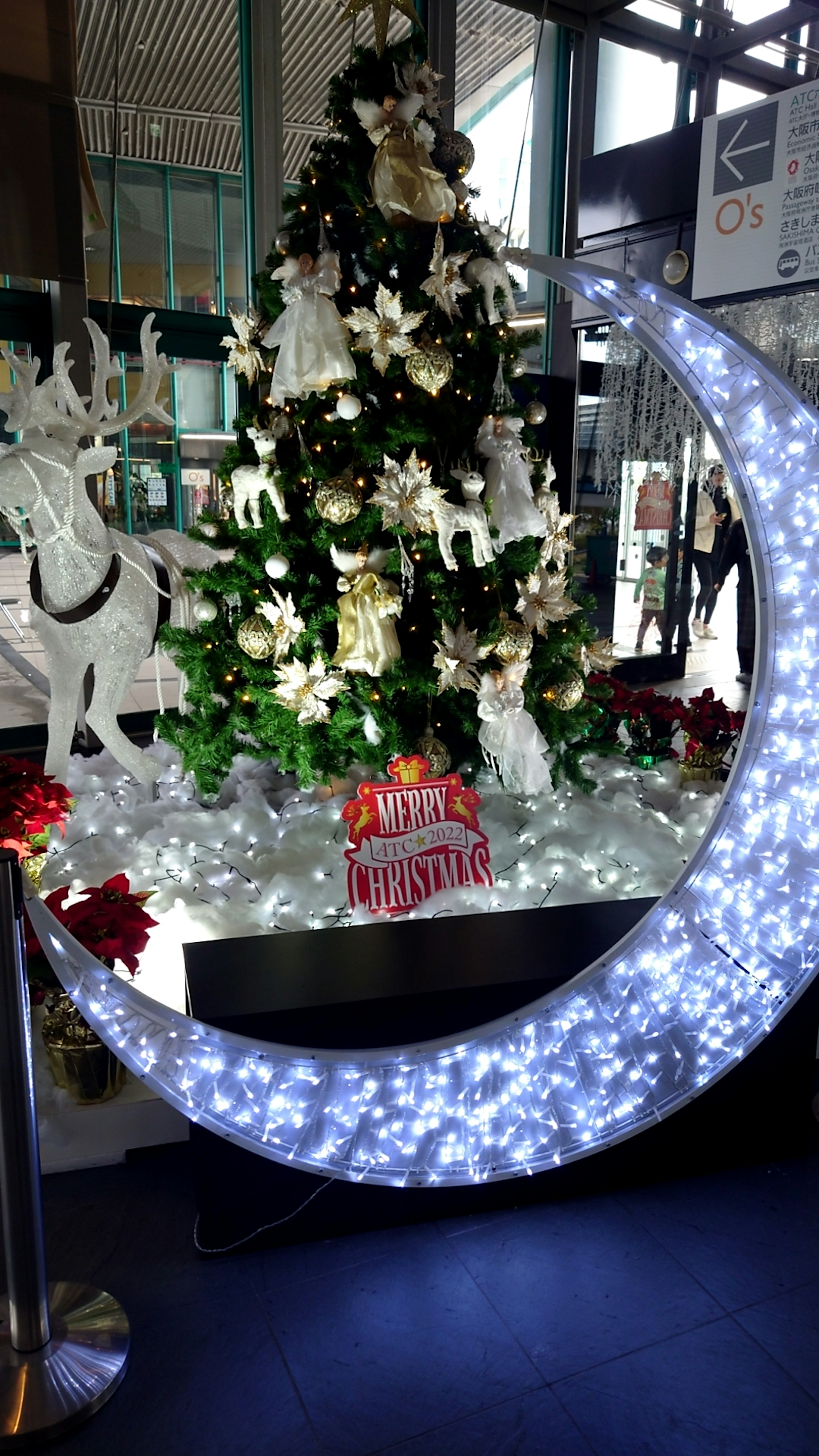 Décoration en forme de lune lumineuse près d'un sapin de Noël et d'un renne blanc