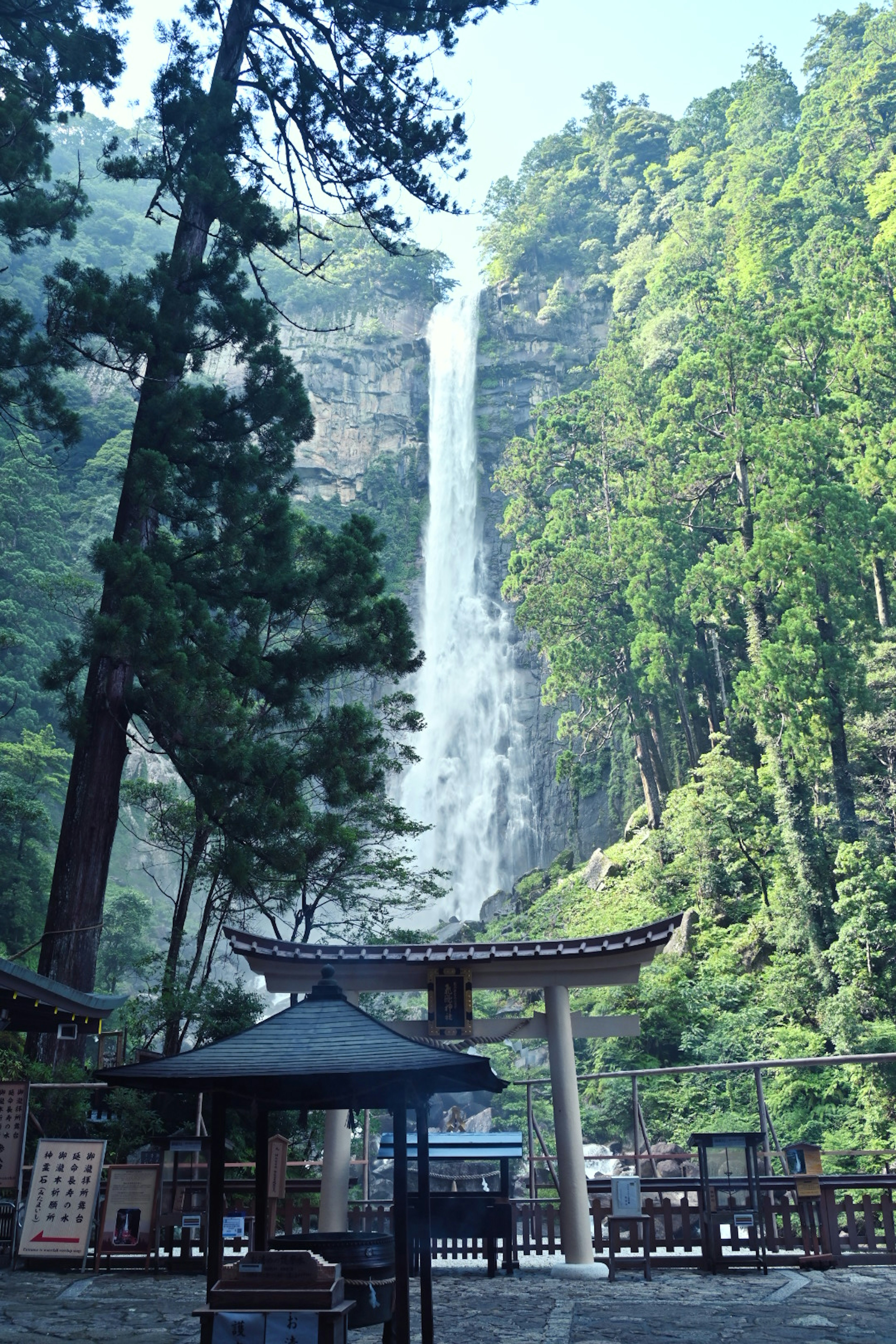 Pemandangan indah air terjun dikelilingi oleh pepohonan rimbun dan arsitektur tradisional