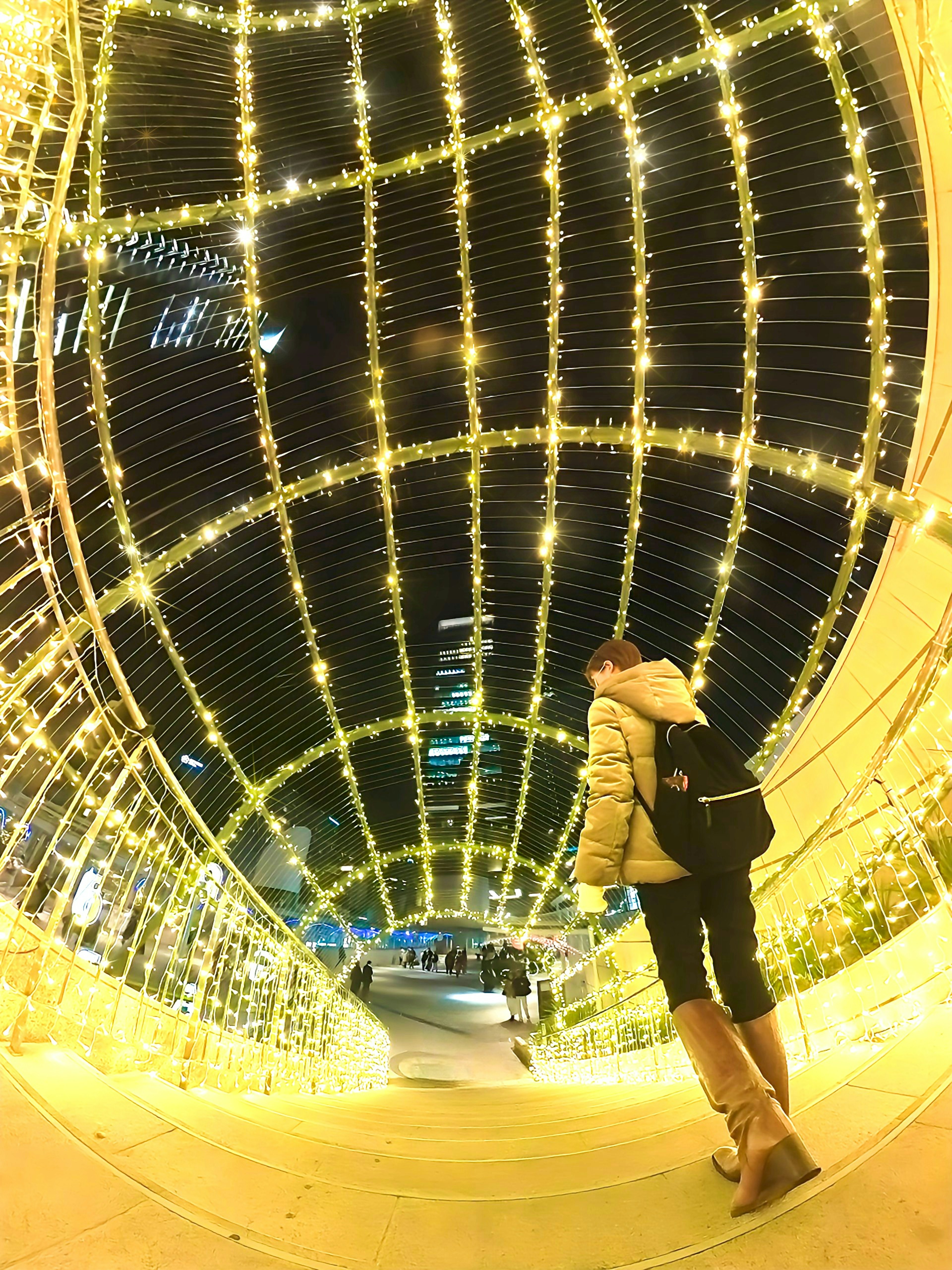 Person walking through a lighted archway tunnel at night