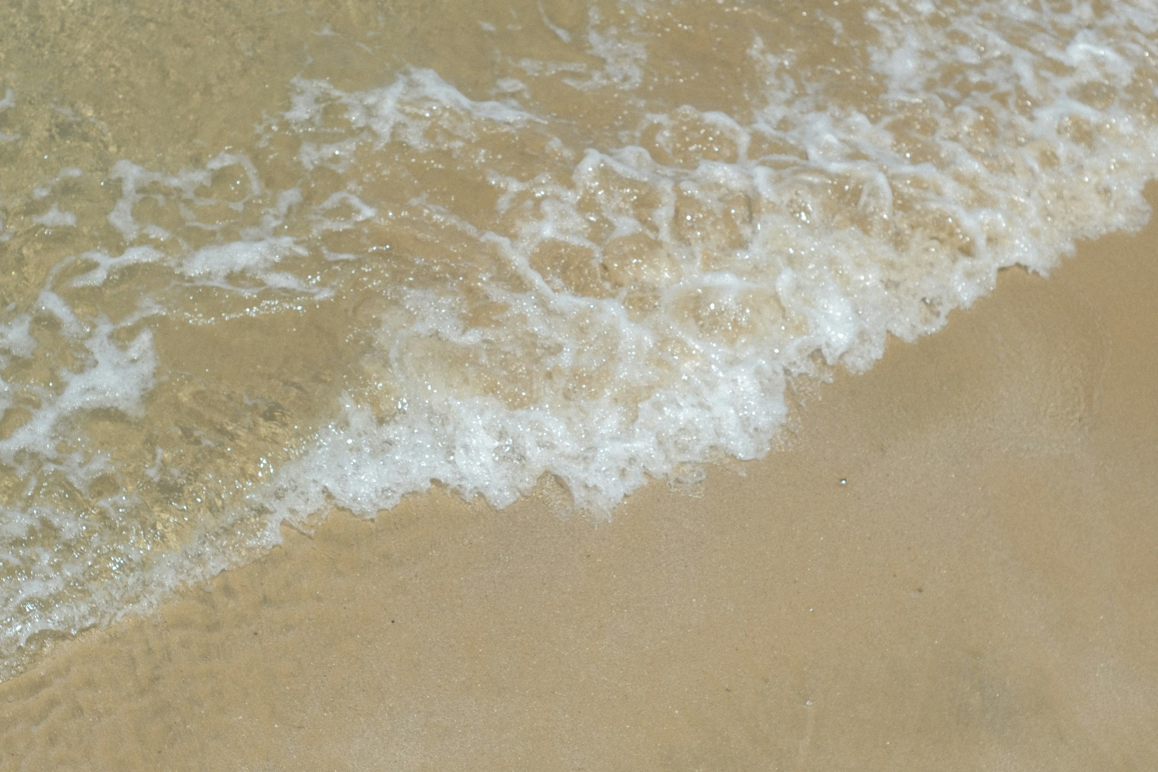 คลื่นอ่อนโยนซัดเข้าชายหาดทราย