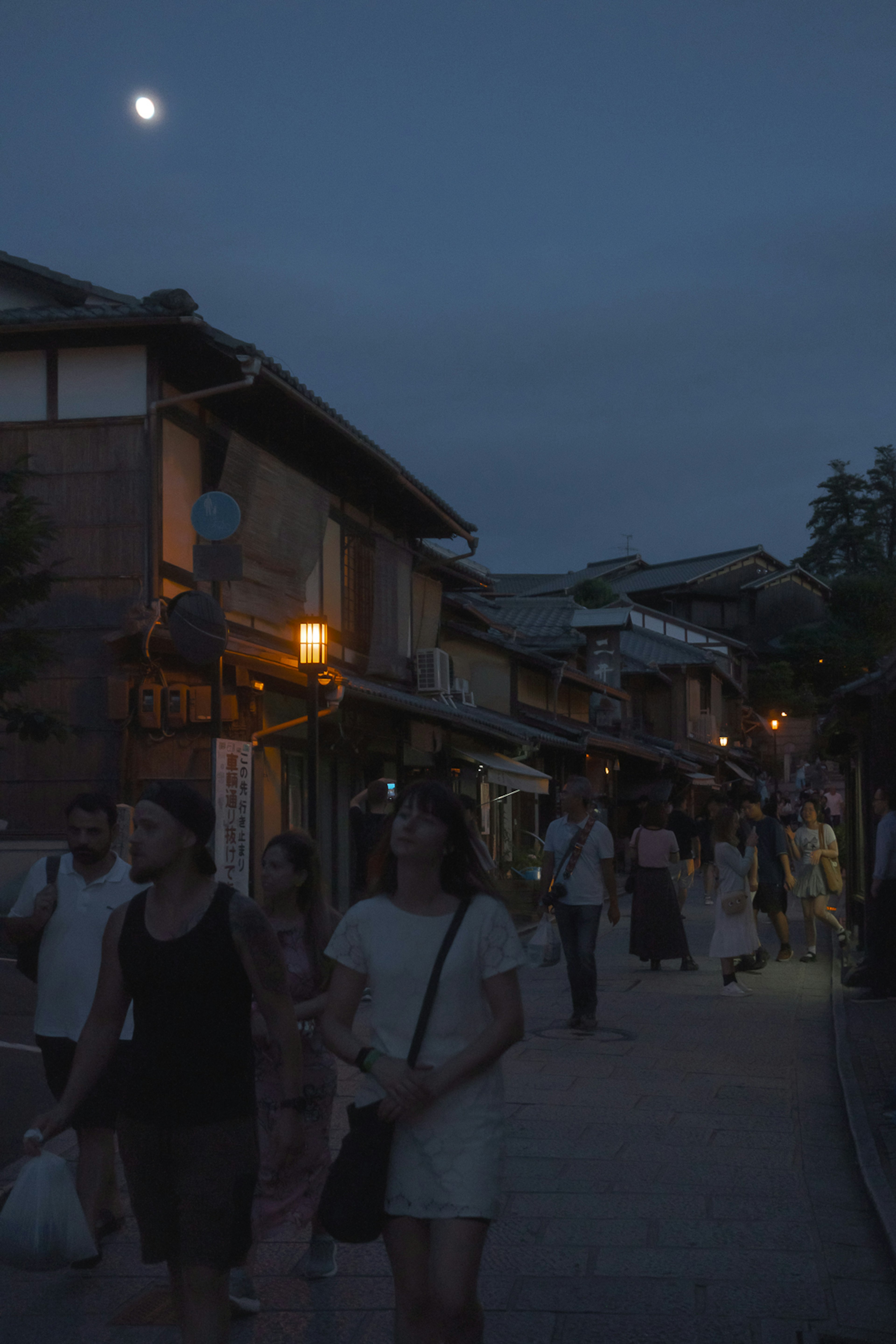 Des gens marchant dans une rue pittoresque sous la lumière de la lune