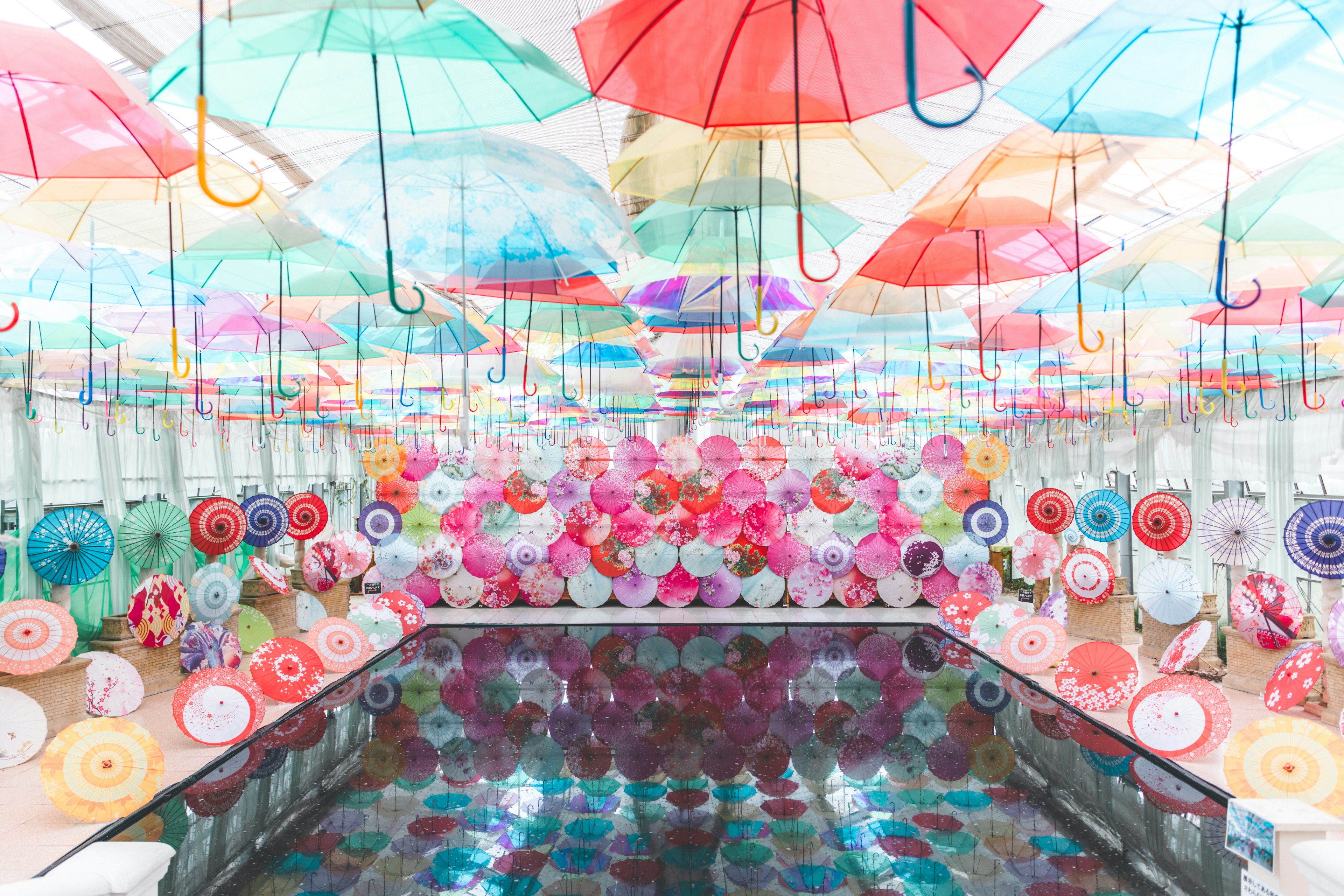 Parapluies colorés suspendus dans un espace vibrant avec une surface d'eau réfléchissante