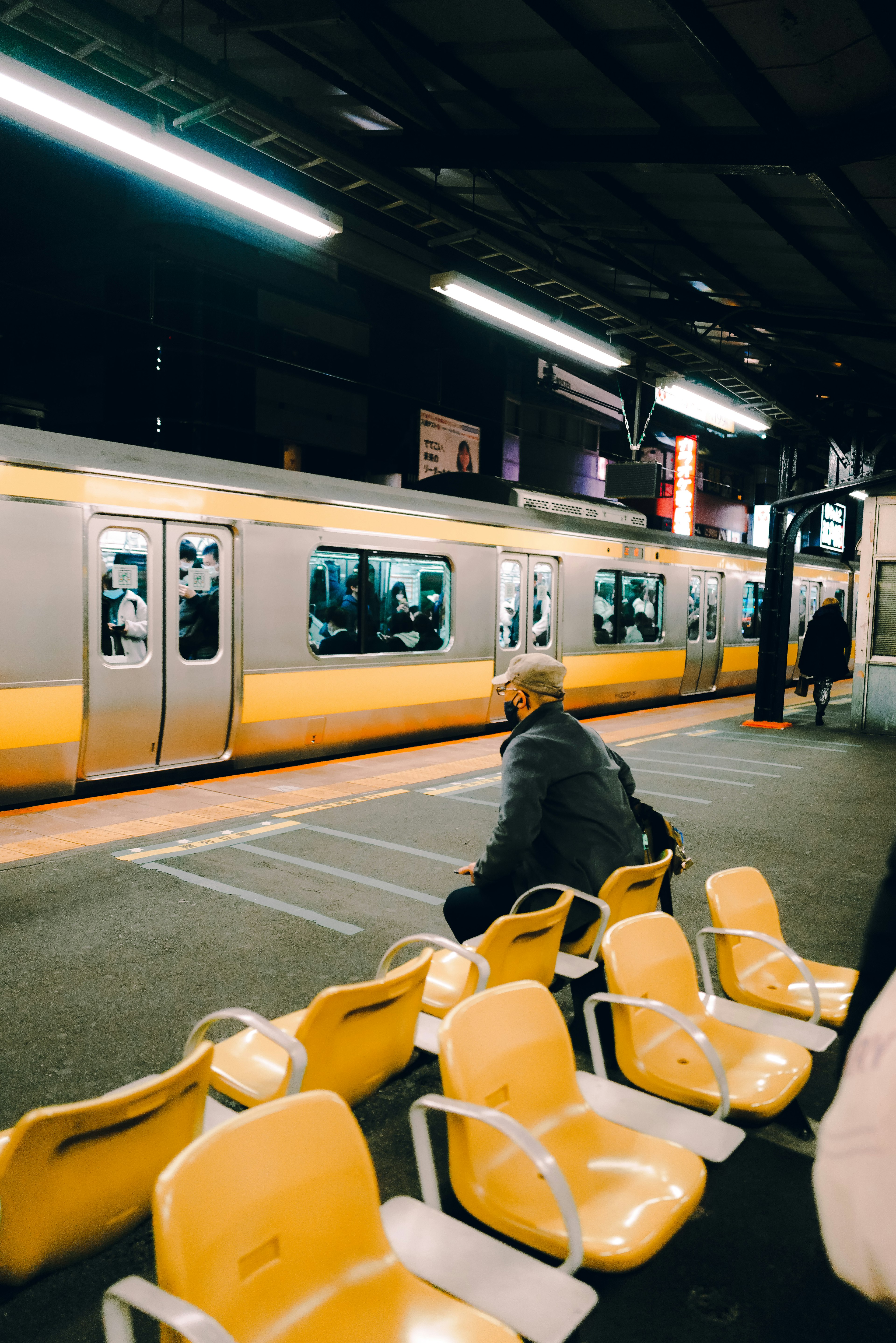 Train at a station platform with a man sitting on yellow seats