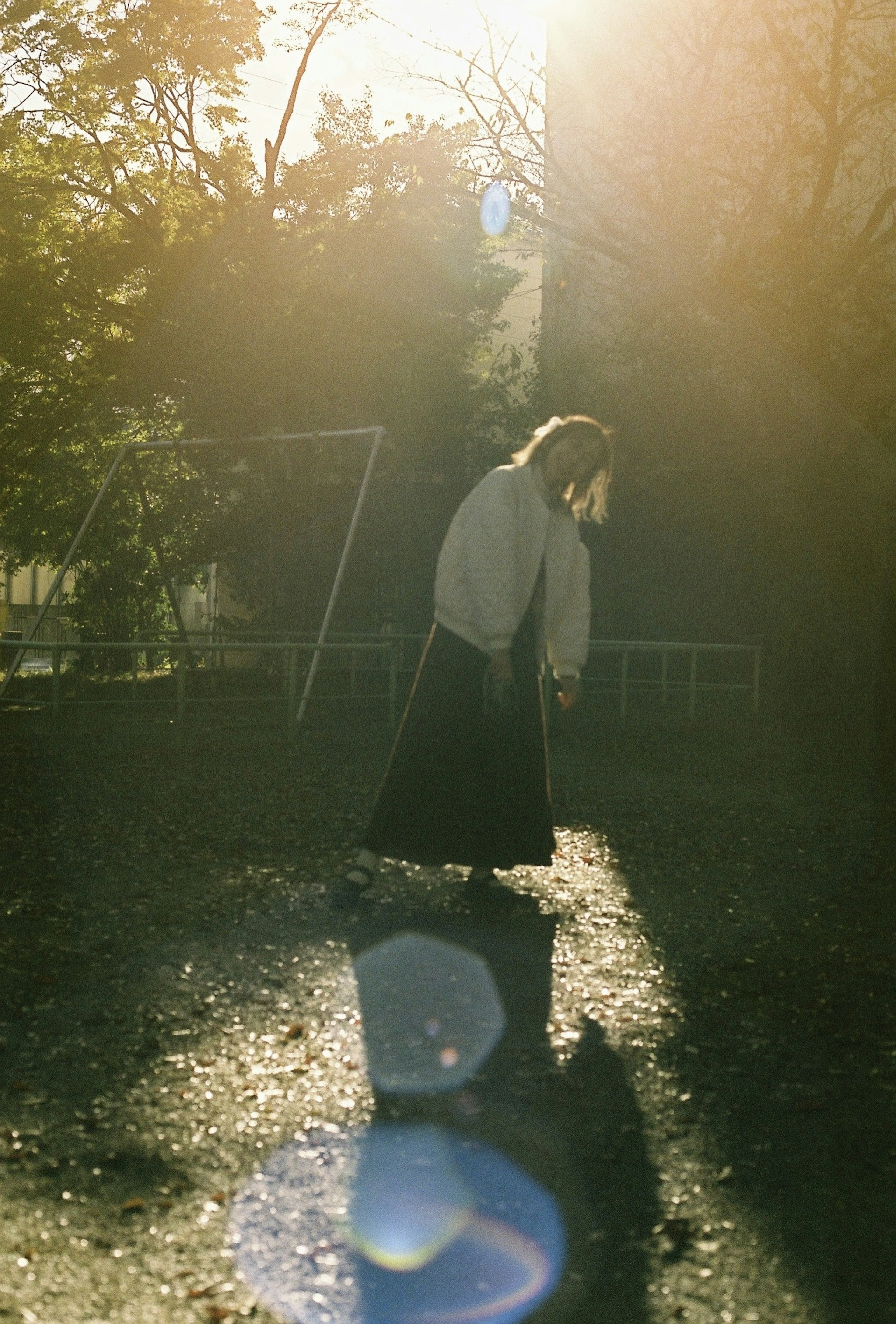 Una persona in piedi in un parco immerso nella luce del tramonto