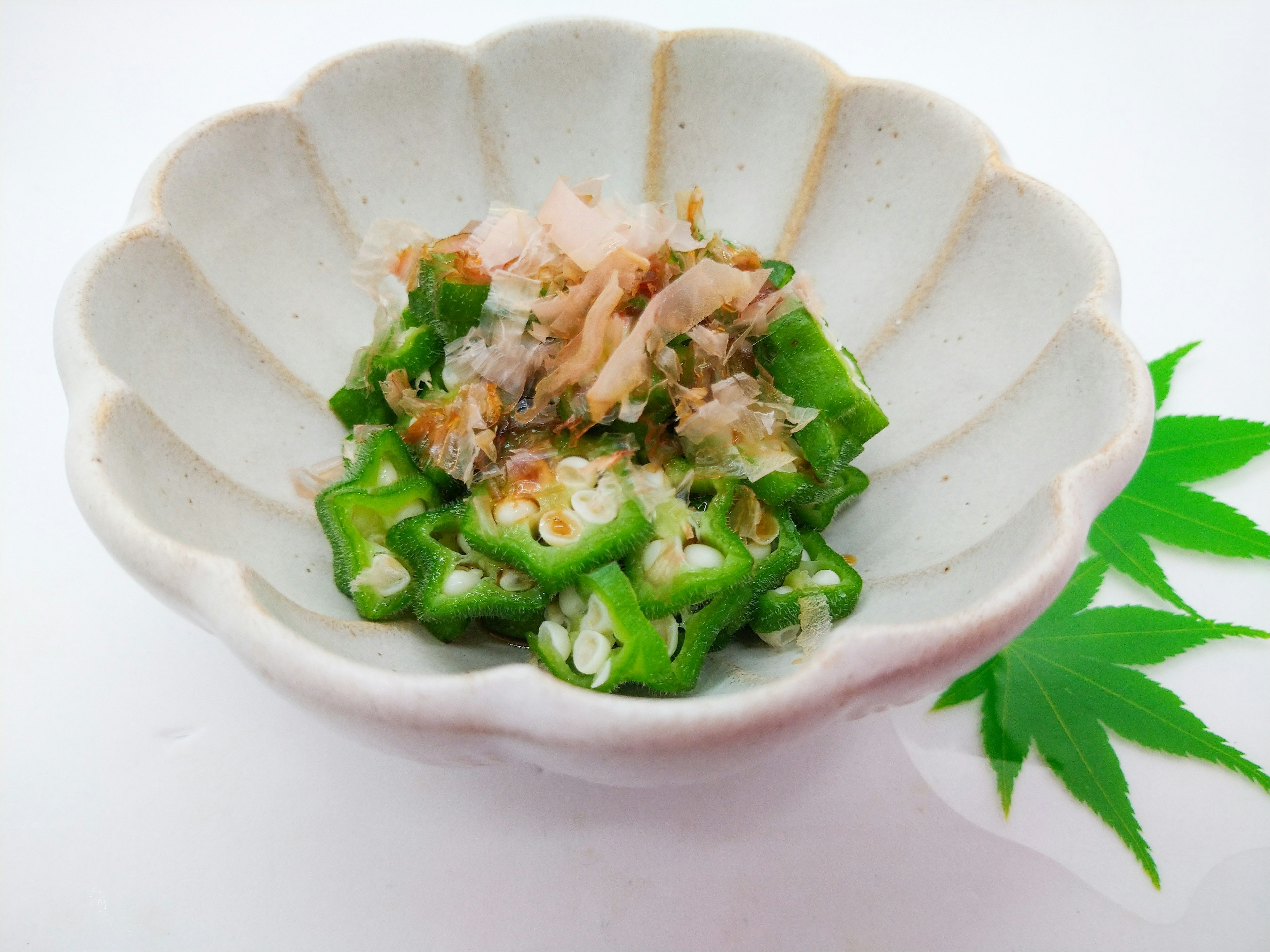 Plat avec des okras verts garnis de flocons de bonito dans un bol blanc