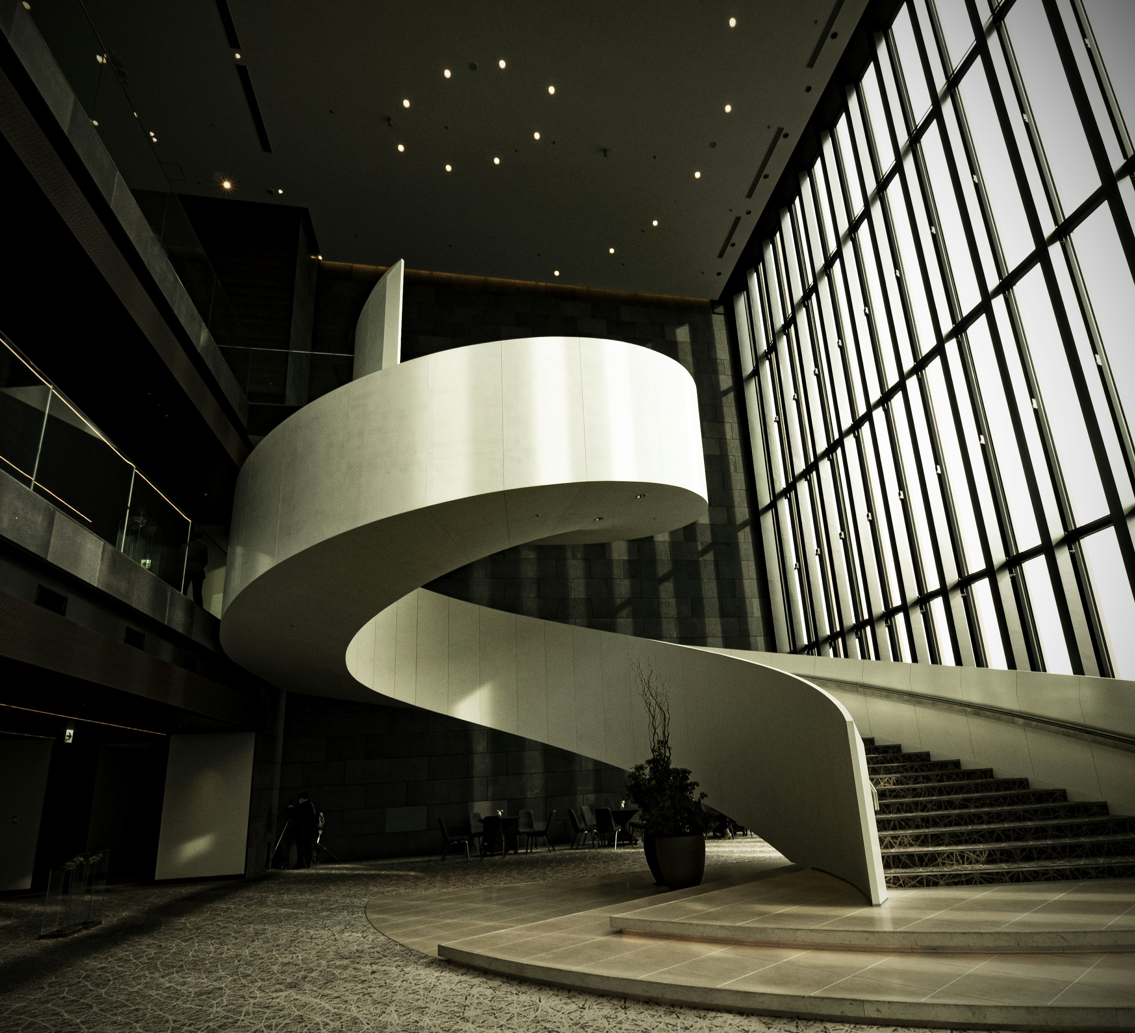 Modernes Interieur mit einer weißen Wendeltreppe und großen Glasfenstern