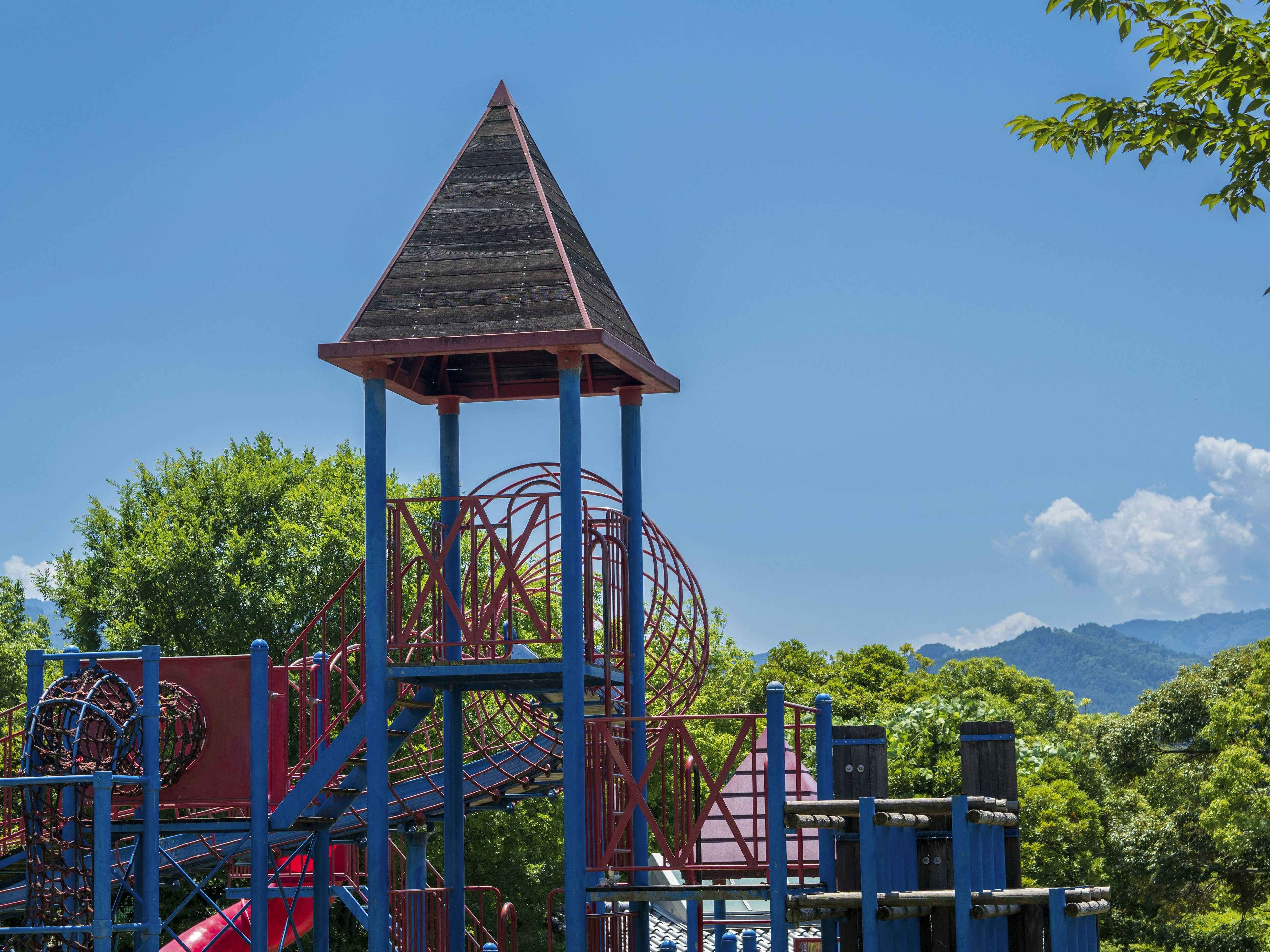 Spielplatzgeräte unter einem klaren blauen Himmel mit grünen Bäumen