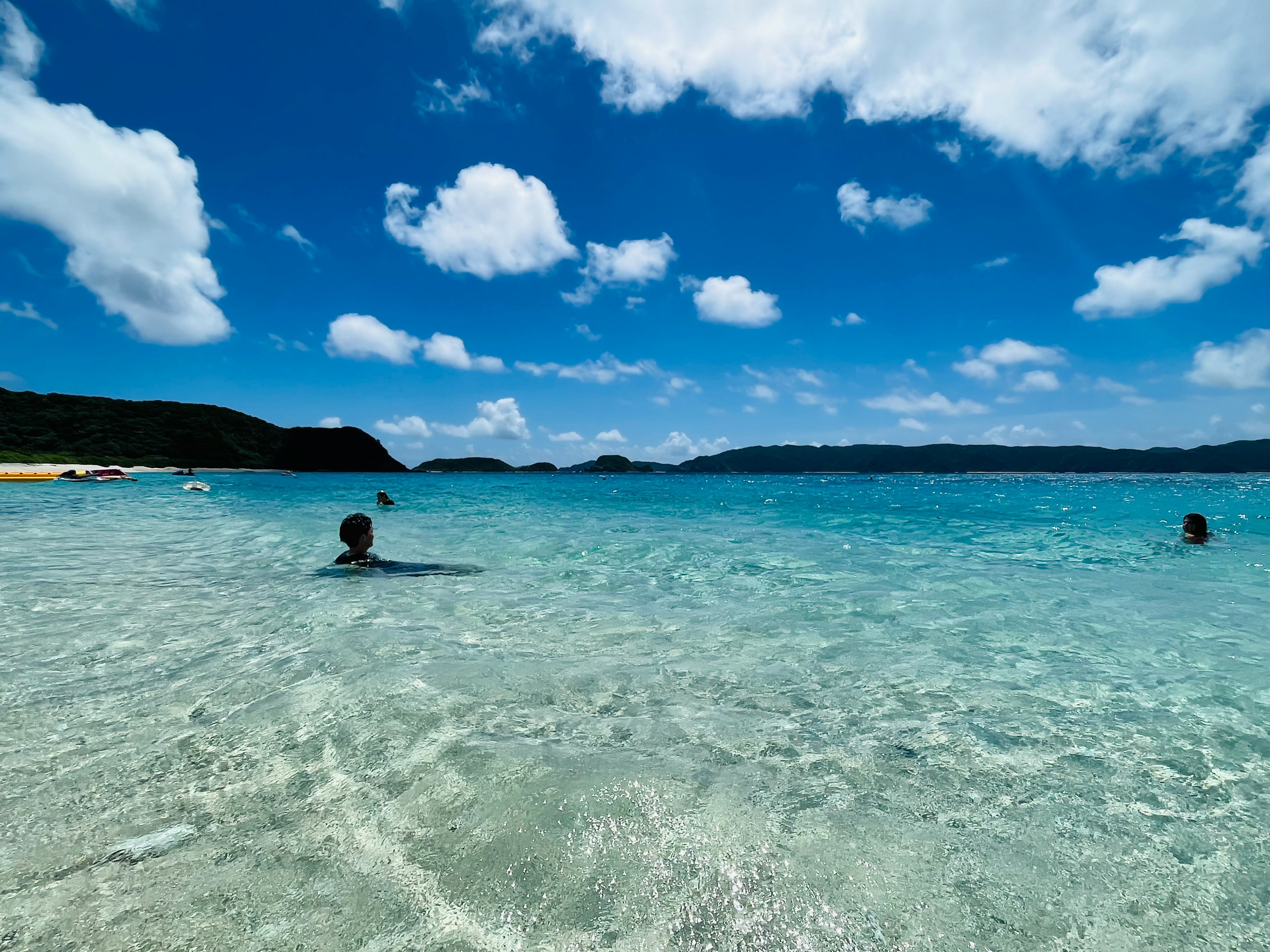 青い海と空が広がるビーチで泳ぐ人々の風景