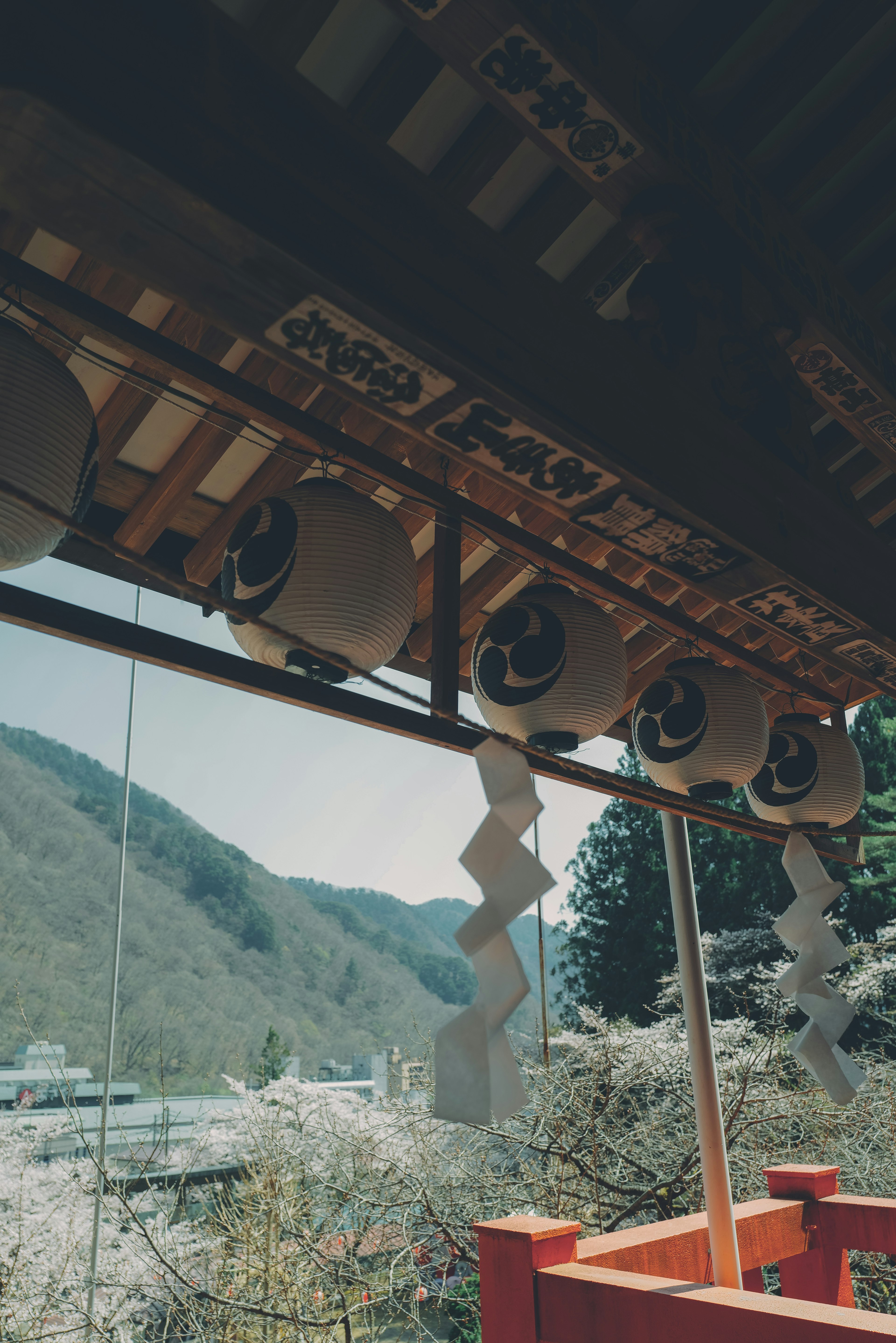 View of lanterns and shide at a shrine with mountains in the background