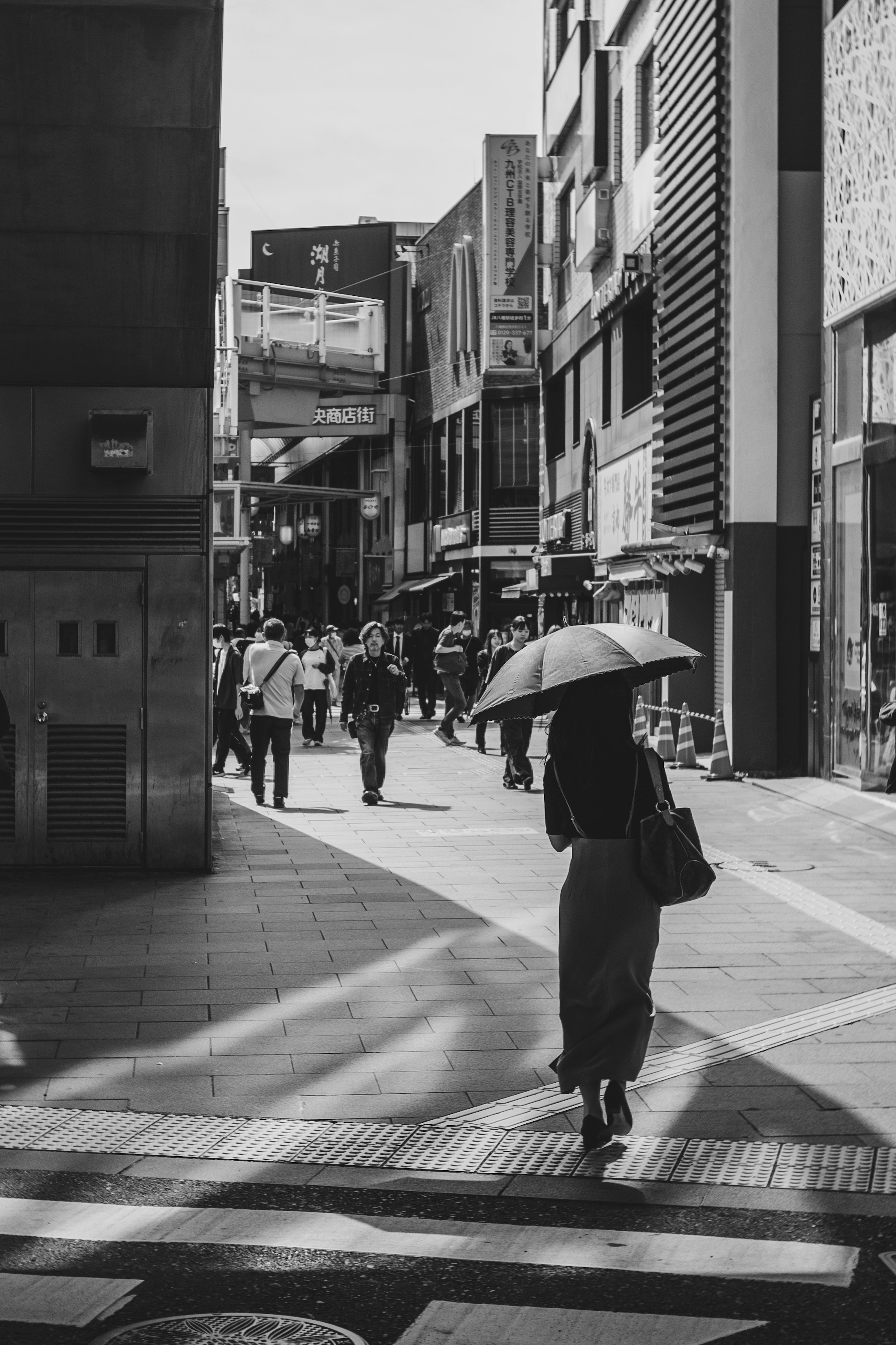 Una mujer caminando con un paraguas en un entorno urbano en blanco y negro