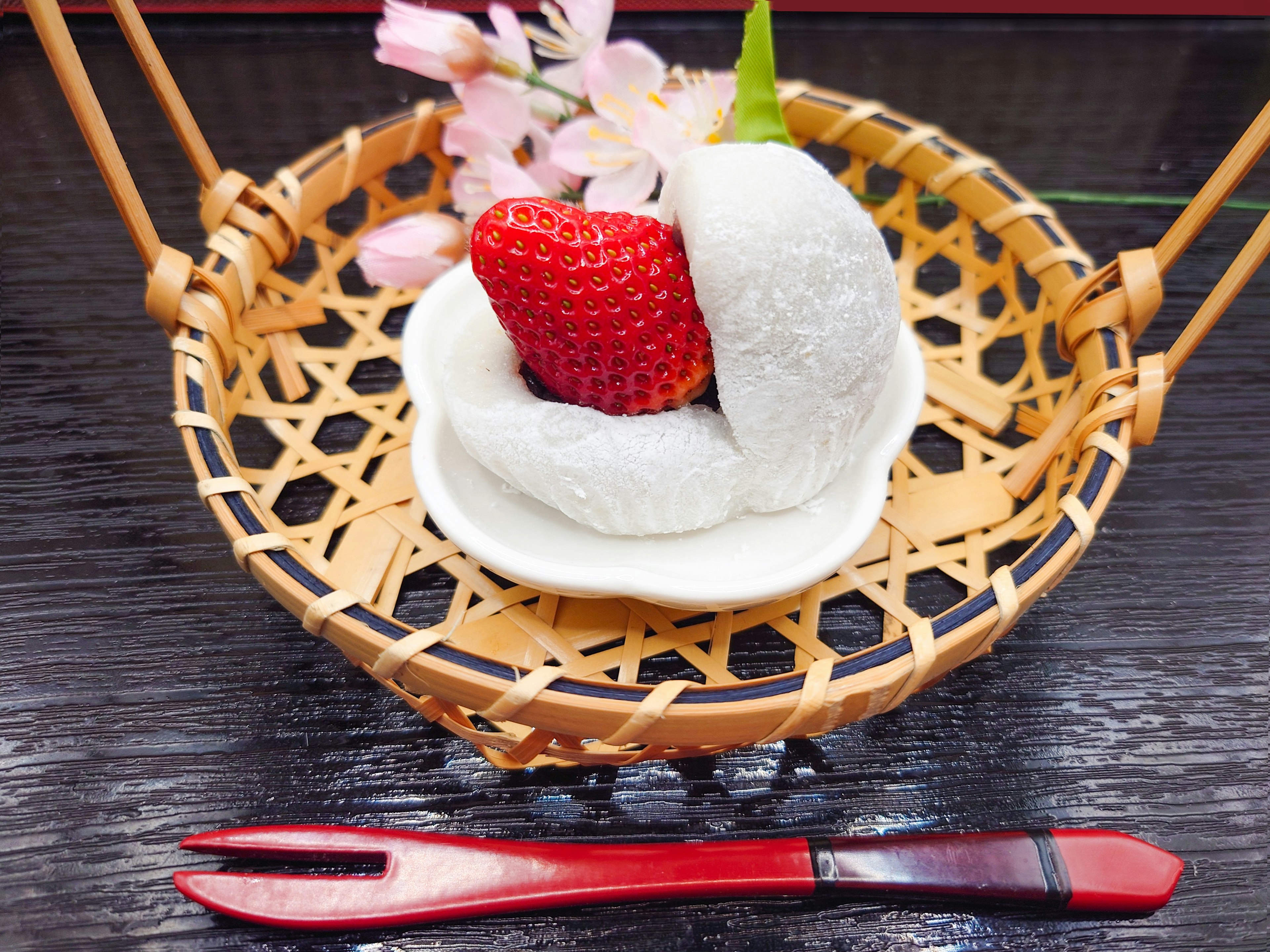 Strawberry daifuku served in a bamboo basket with flowers