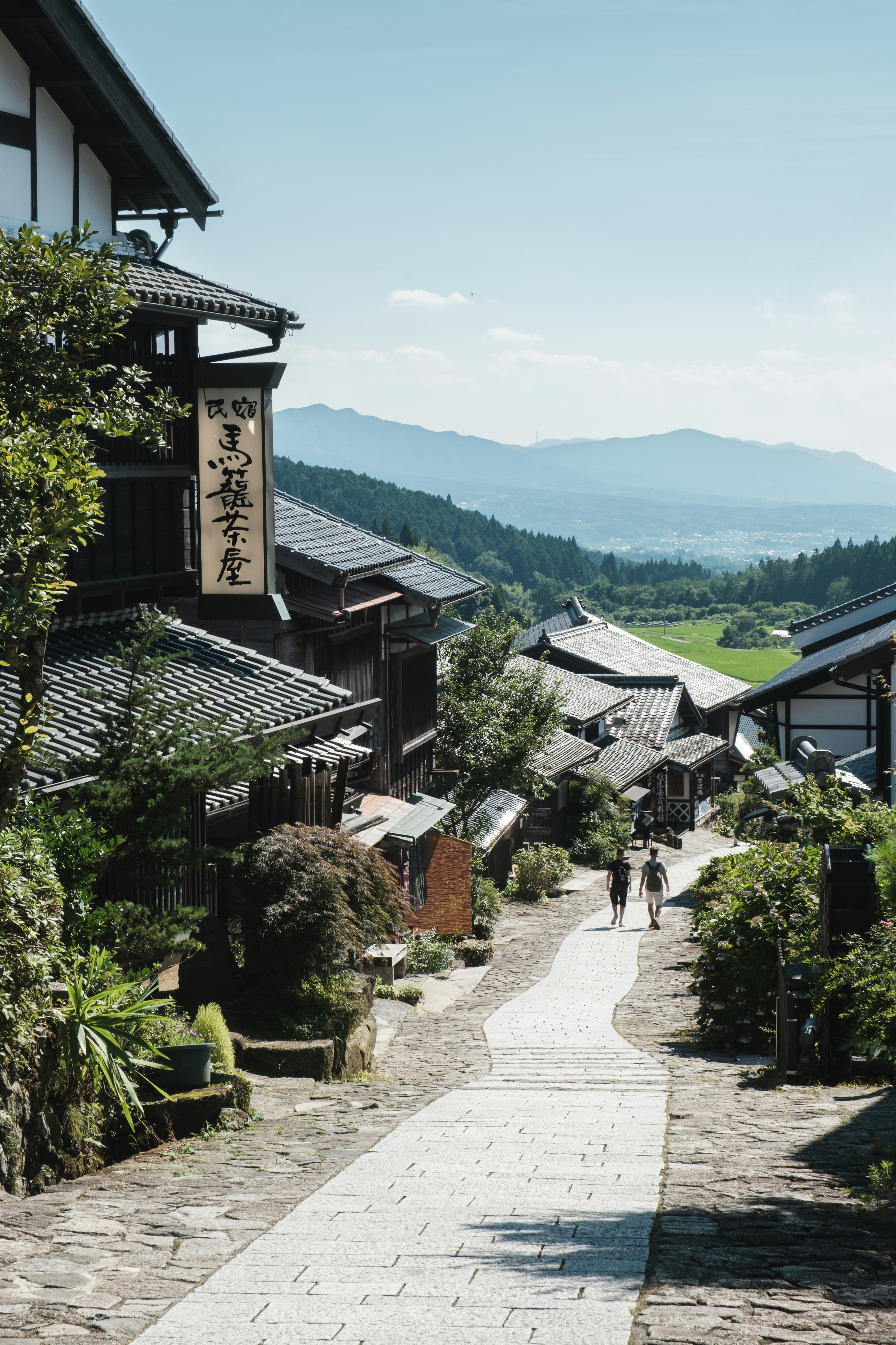 Scenic view of a mountain town with a stone path and people walking