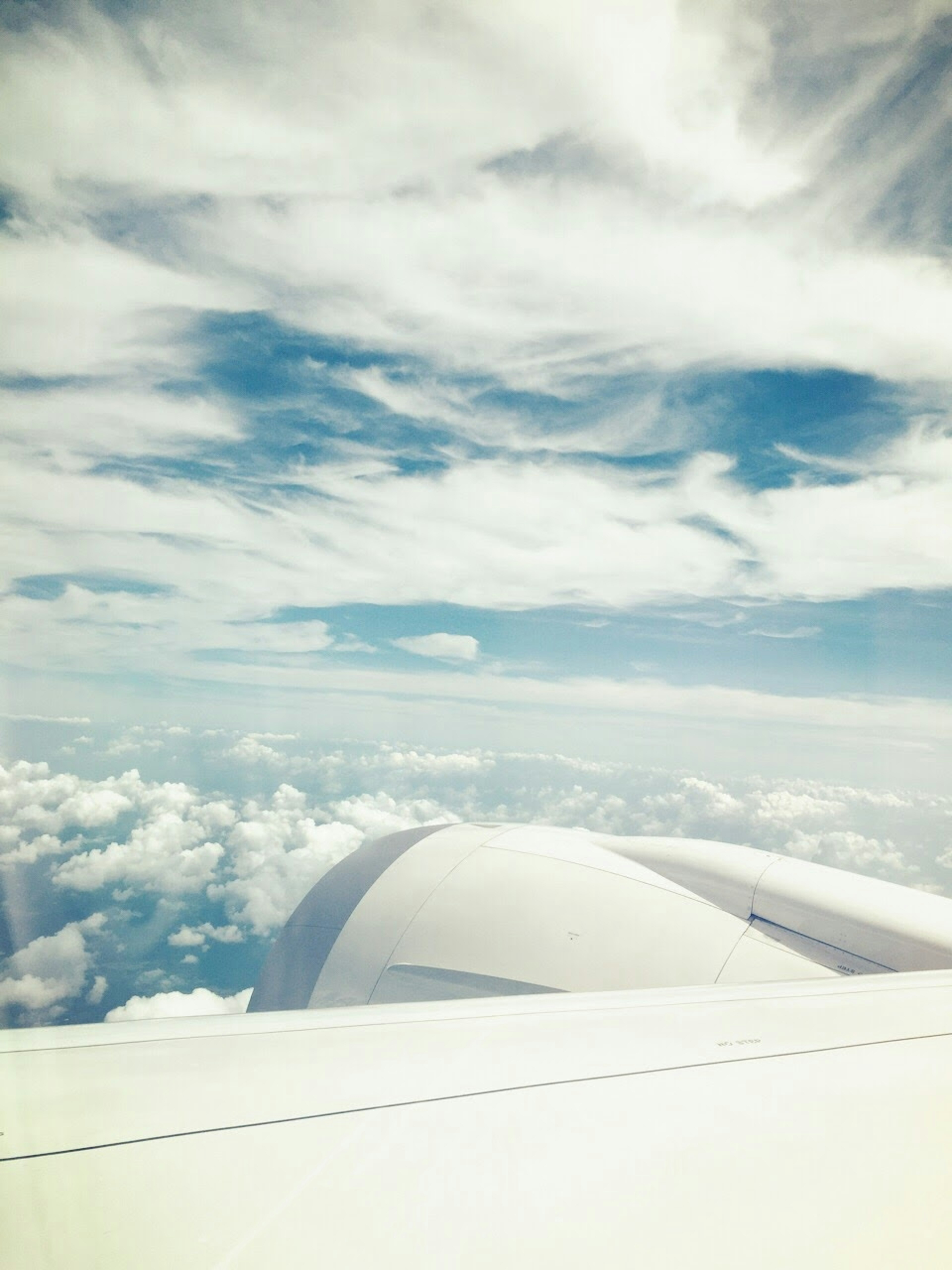 Airplane wing with clouds and blue sky in the background