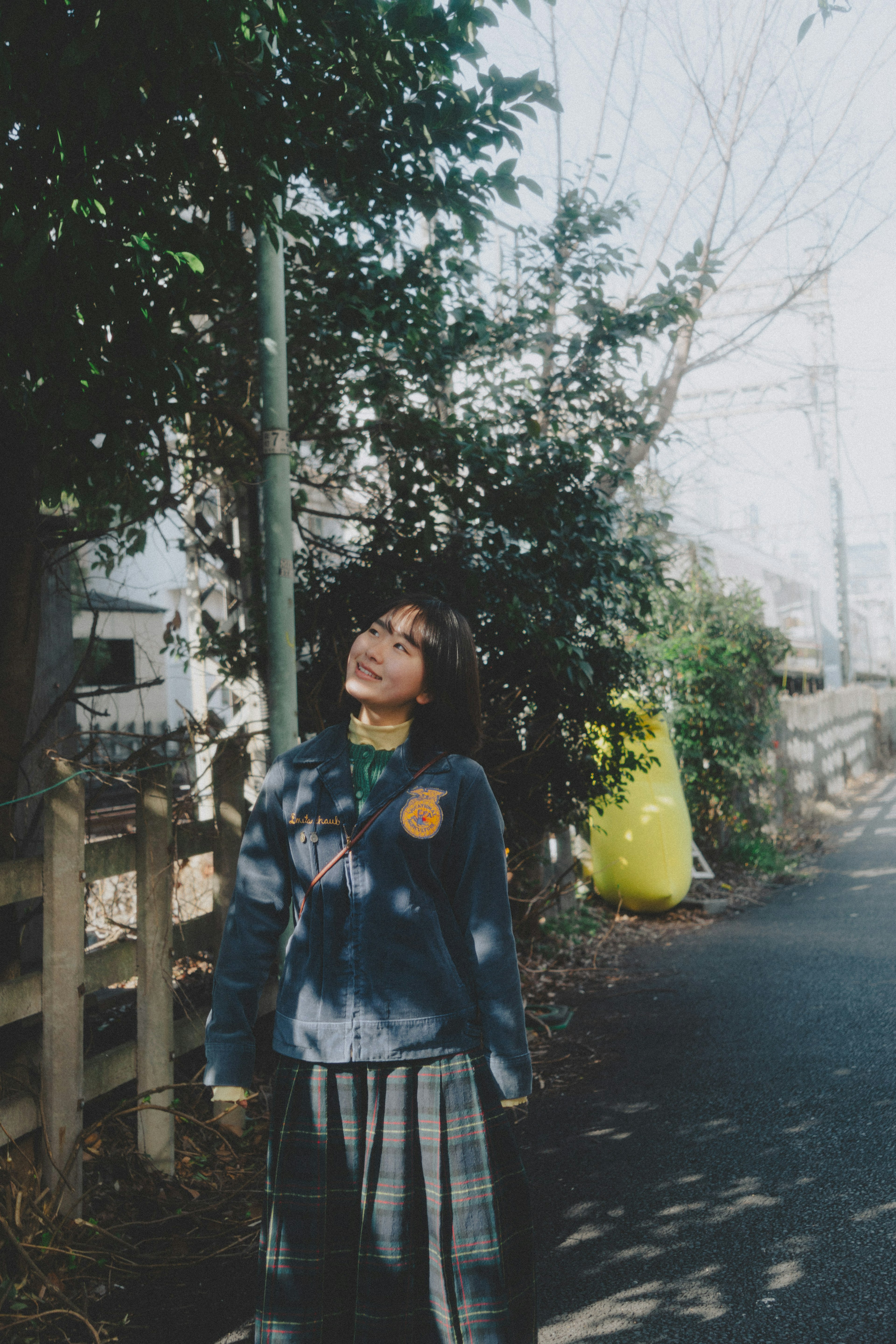 若い女性が木々の間で空を見上げている街の風景