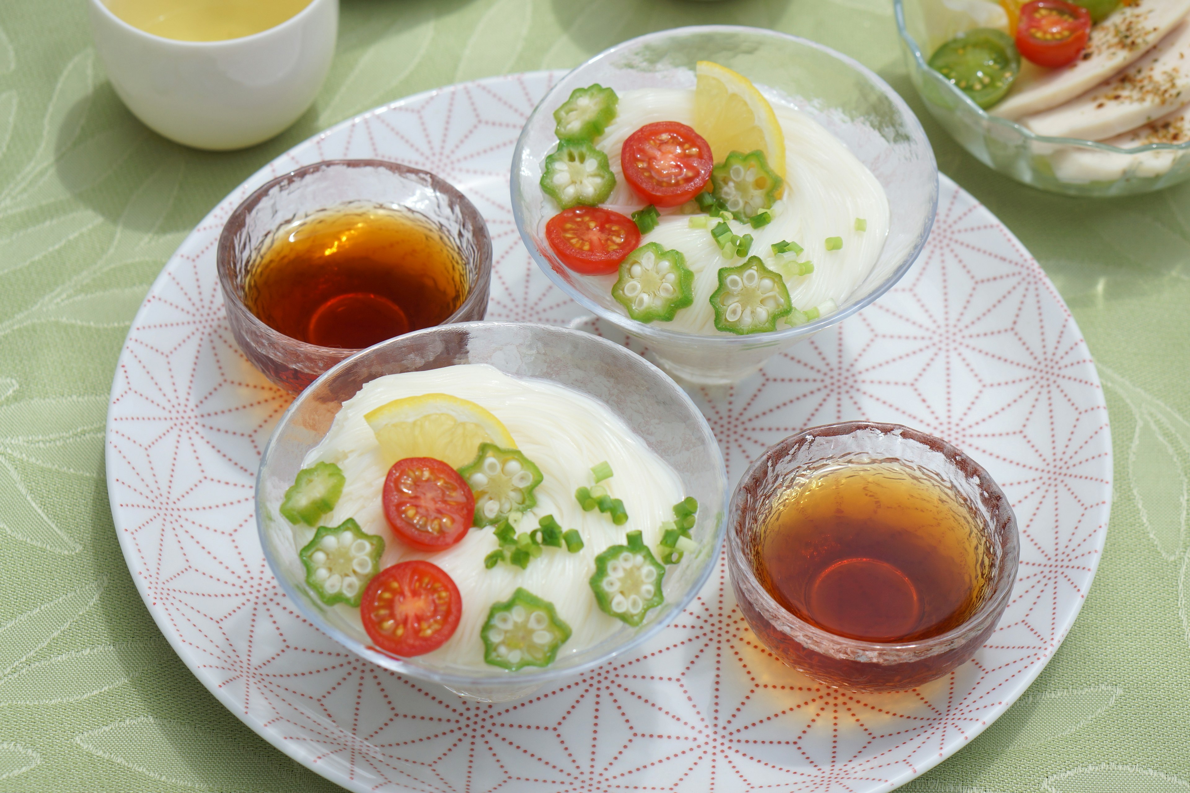 Bowls of creamy yogurt topped with tomatoes and okra served on a decorative plate