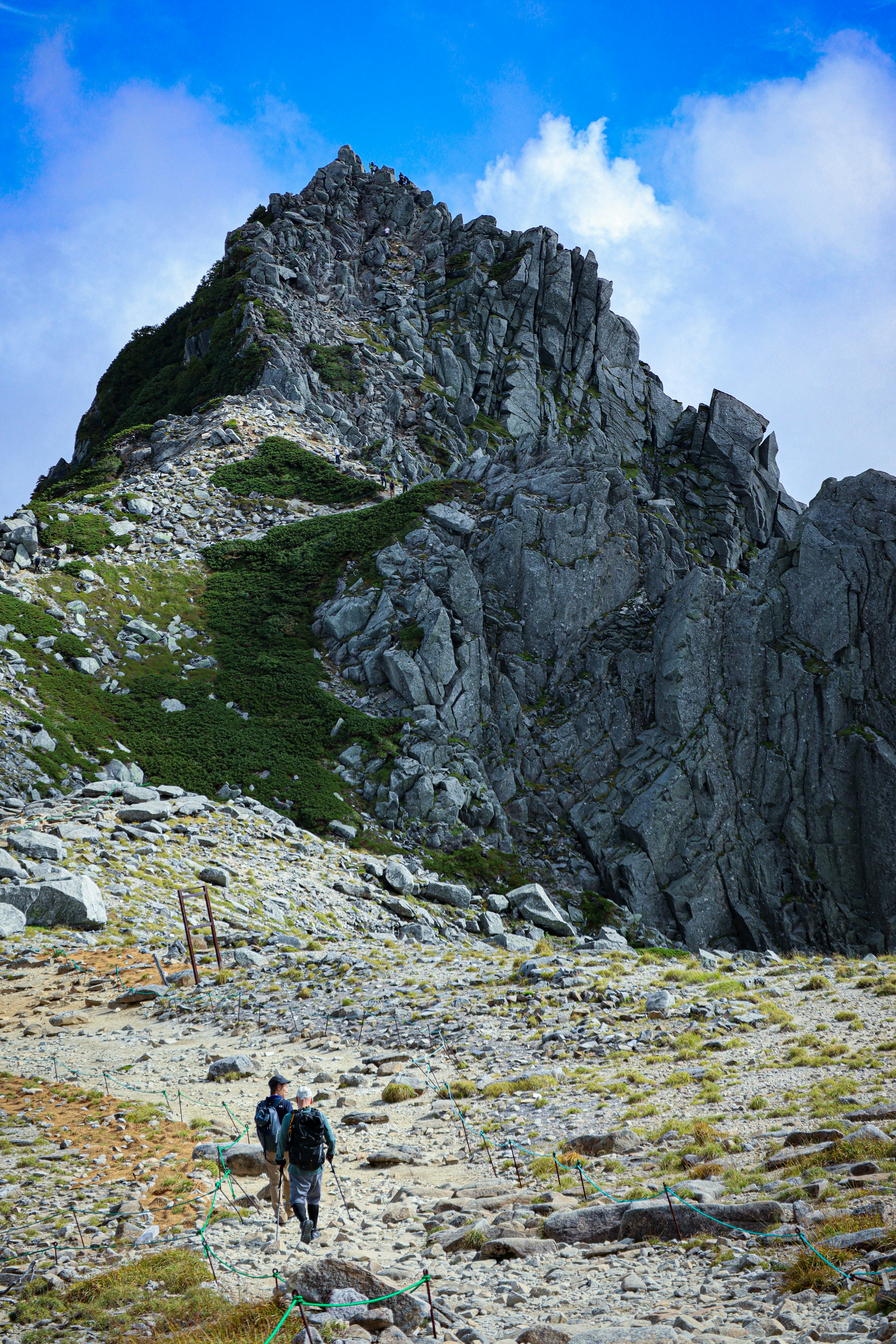 在崎嶇小徑上行走的登山者和背景中的雄偉岩山