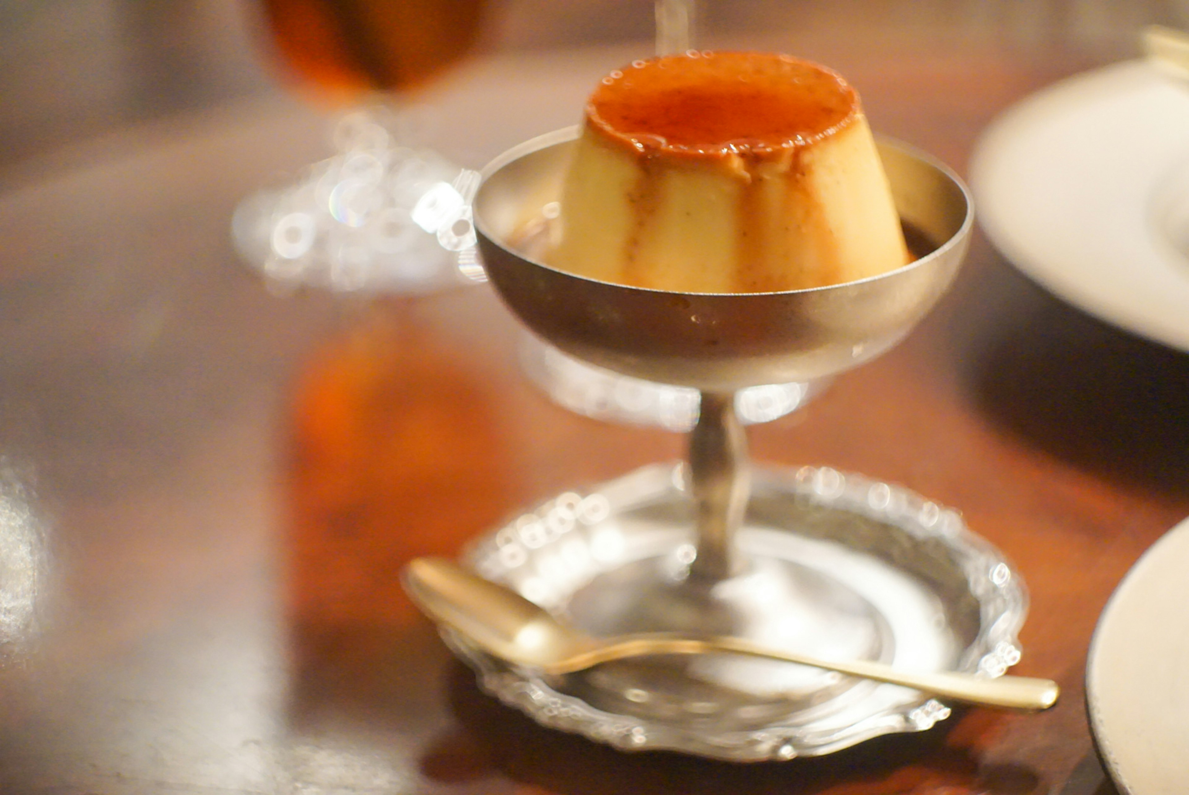 Pudding au caramel servi dans un plat en argent avec une cuillère