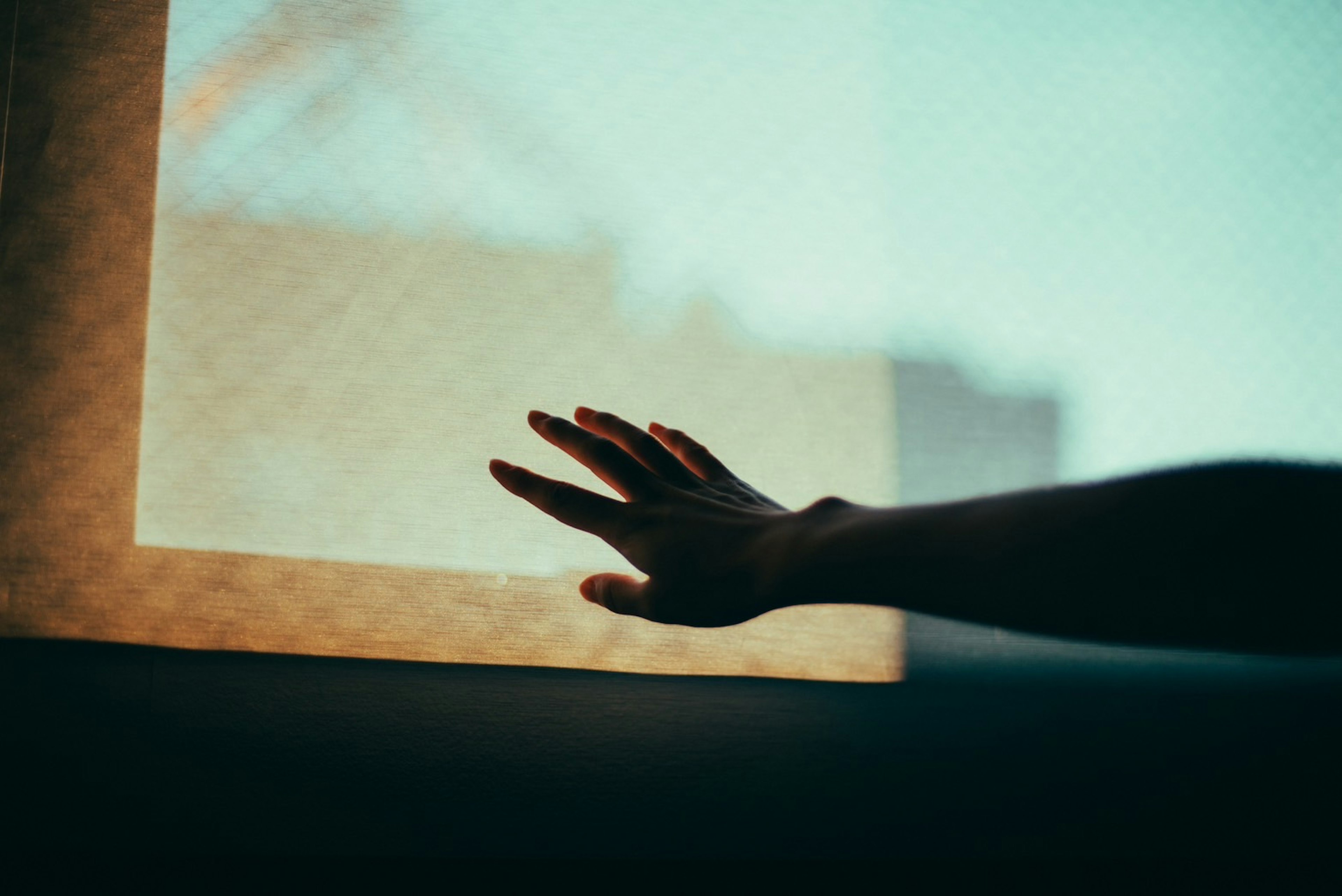 Silhouette di una mano che si estende verso una finestra