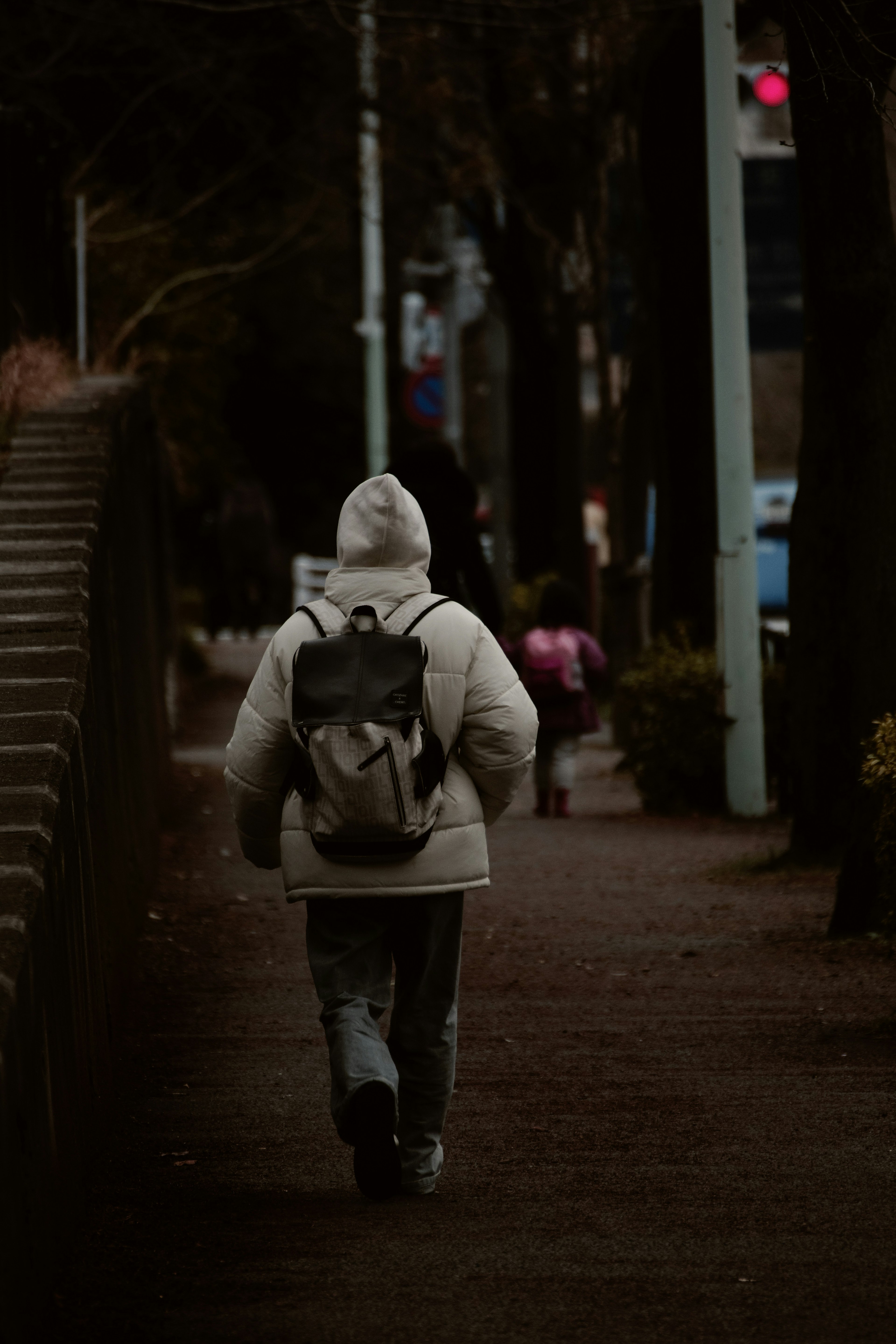 穿著白色連帽外套的人在黑暗的道路上行走