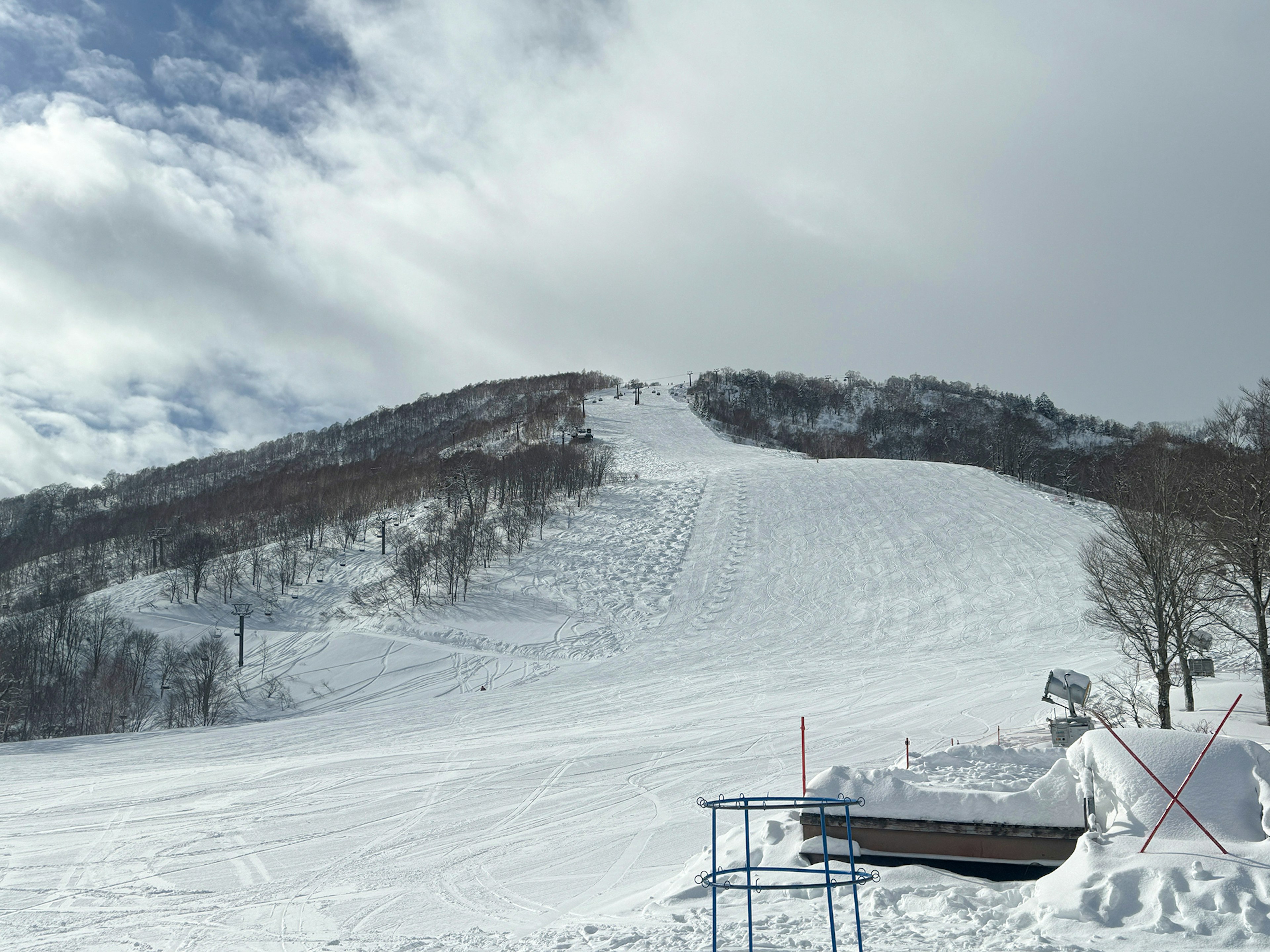 Pista da sci coperta di neve con un mix di cielo blu e nuvole