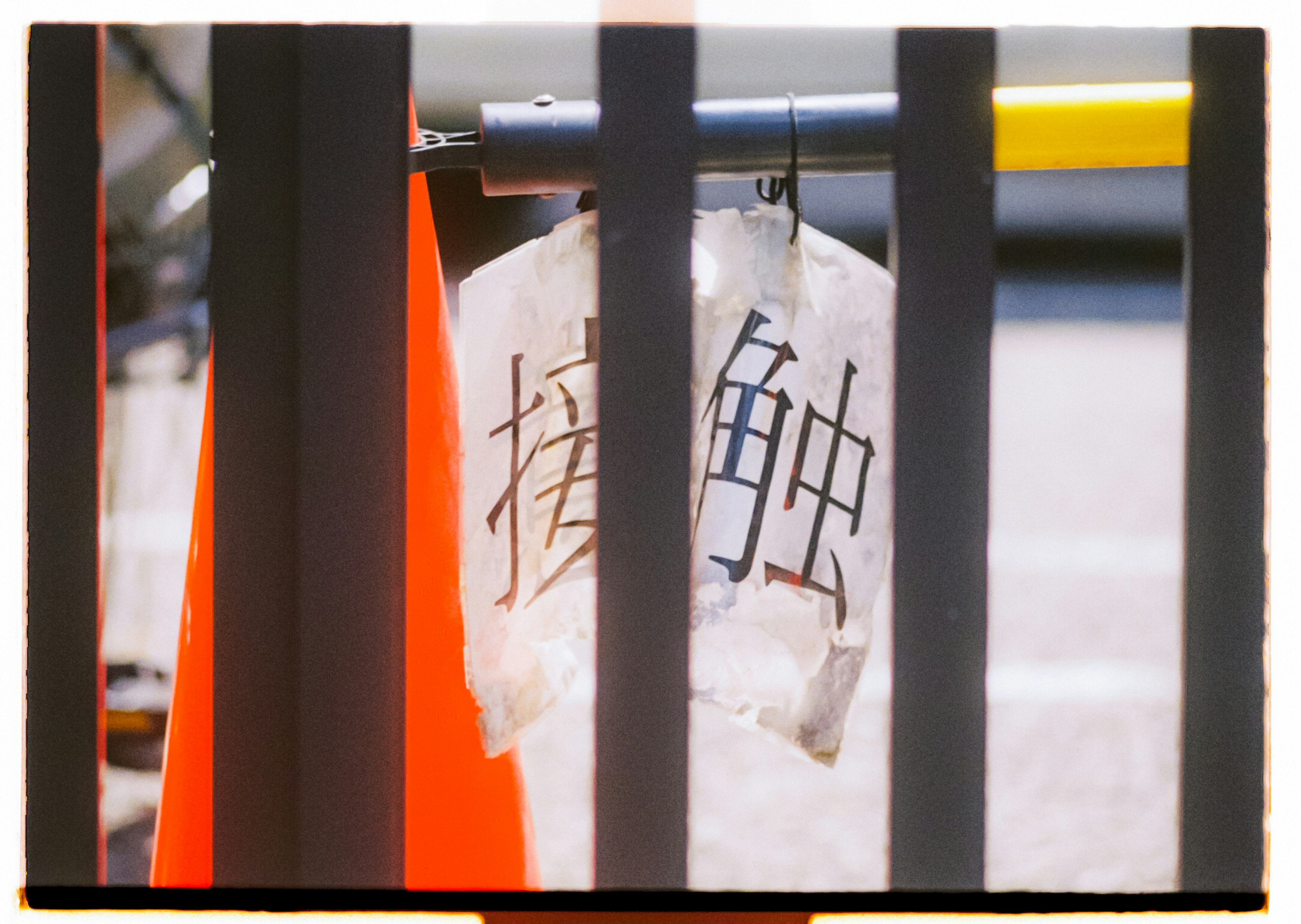 A transparent bag hanging on a fence with characters and an orange cone