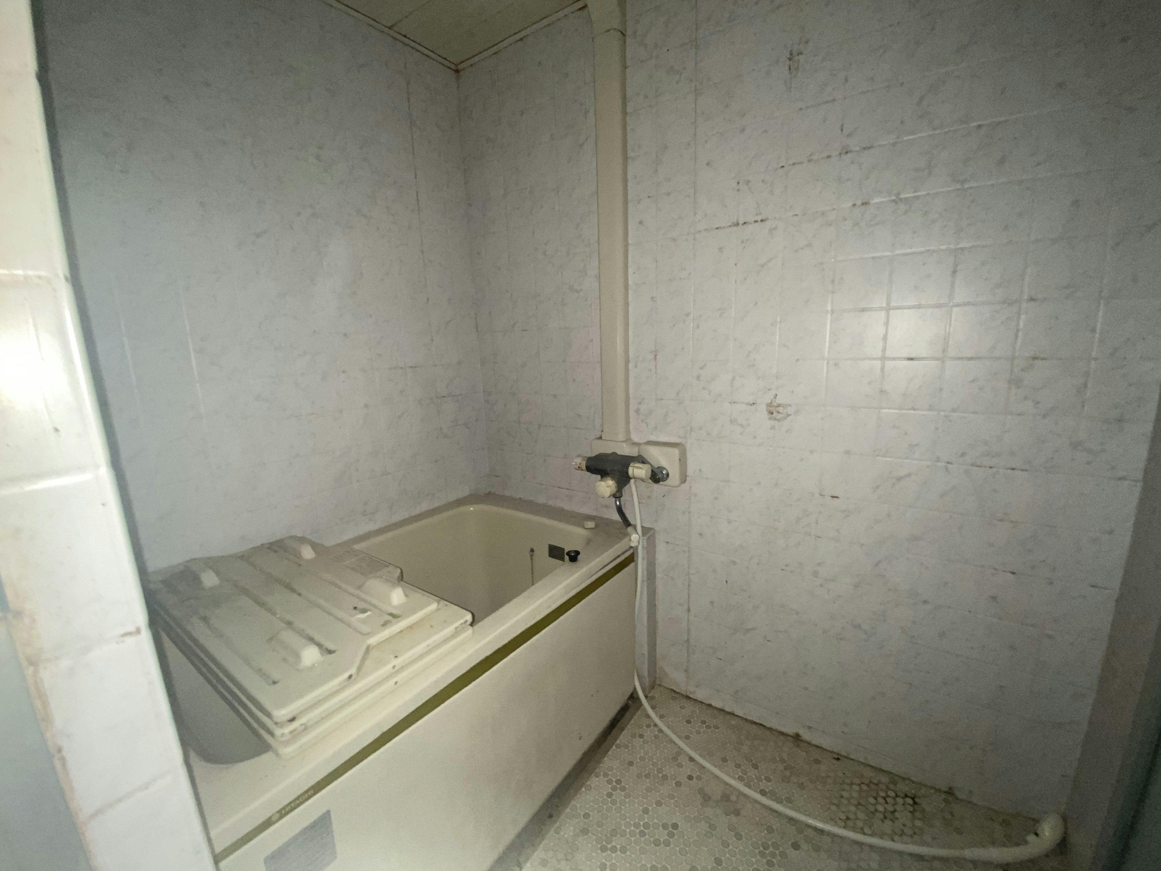 Salle de bain étroite avec des murs carrelés blancs et une machine à laver