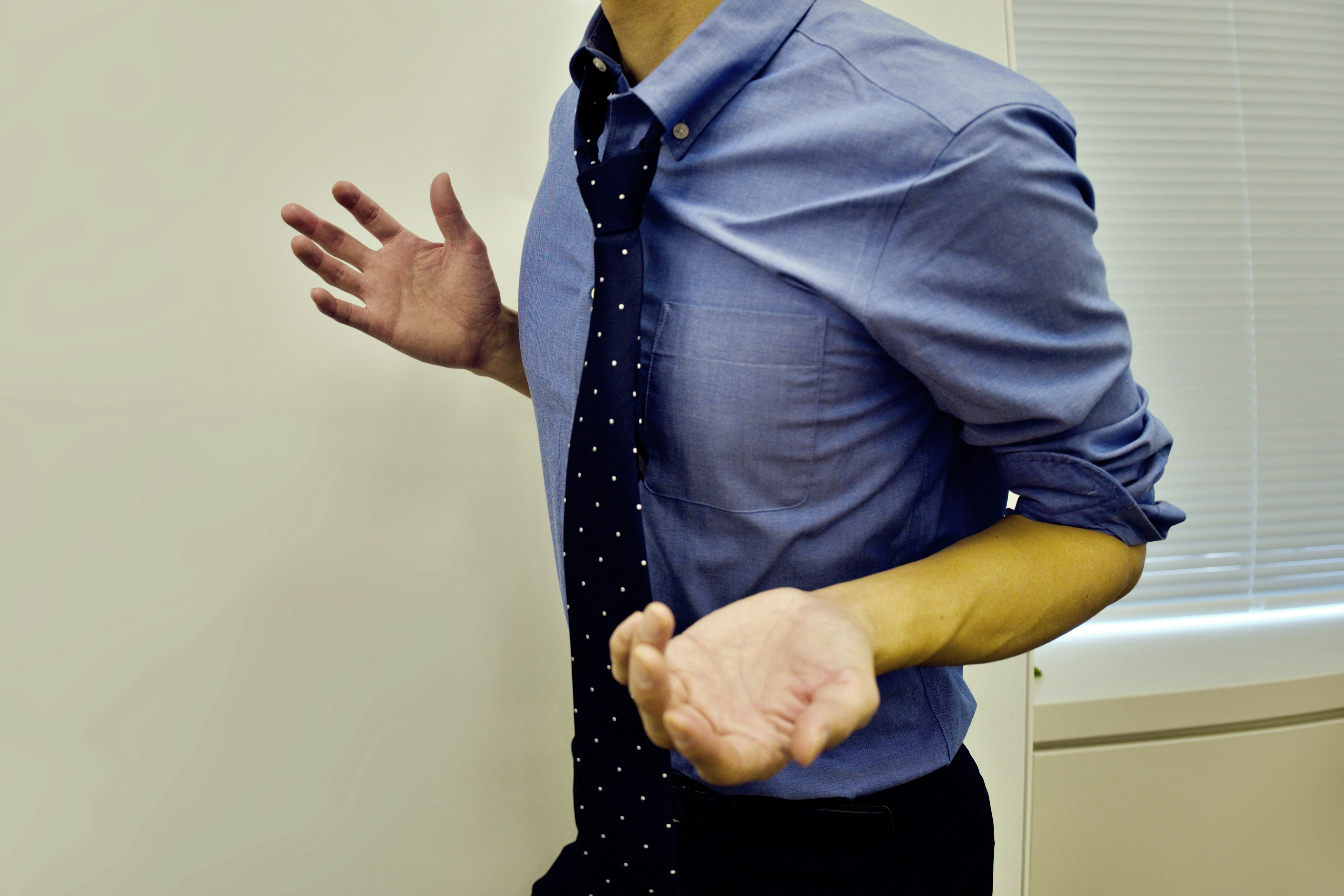 Uomo con camicia e cravatta con espressione confusa che tiene le mani aperte