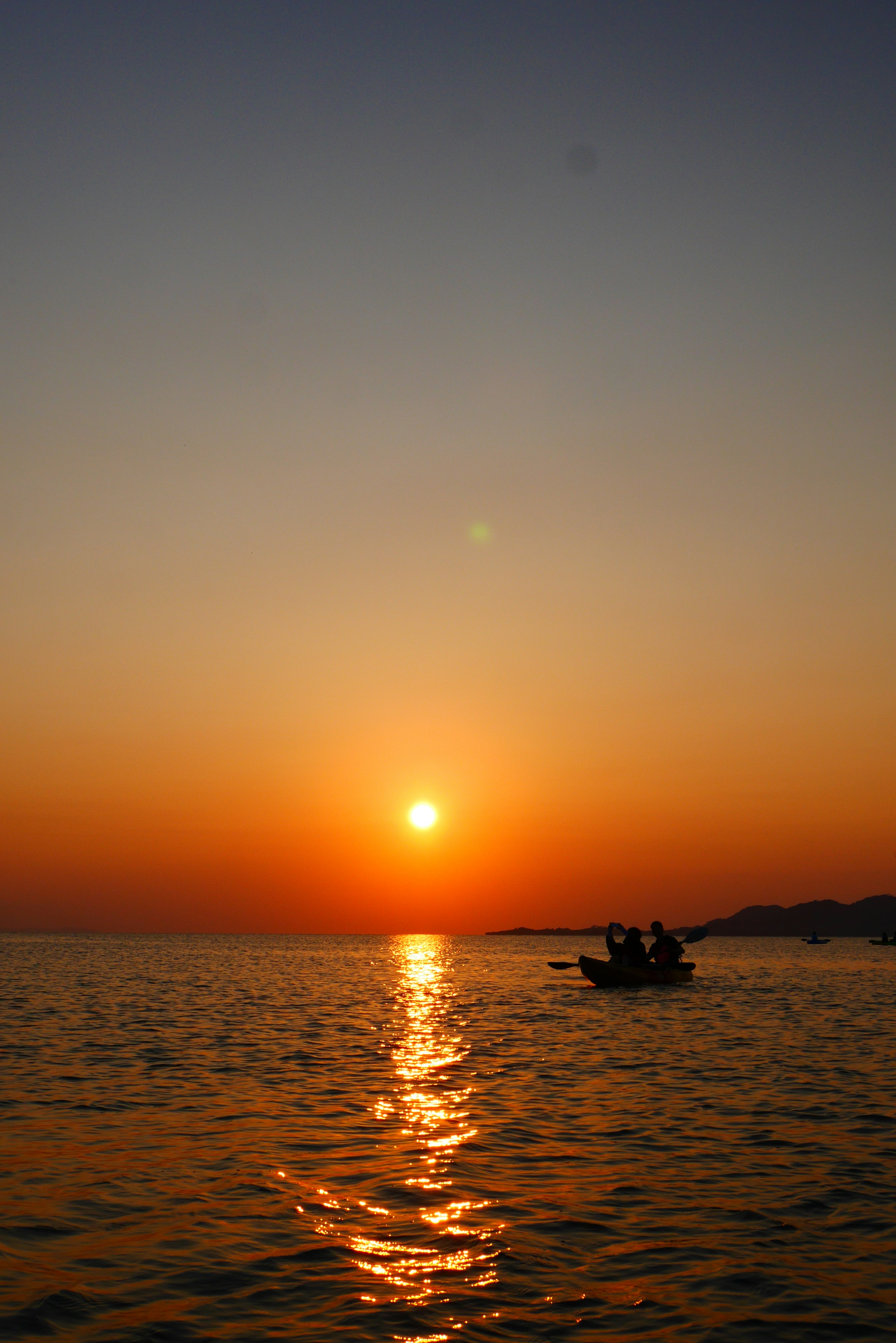 Sunset over the ocean with a small boat