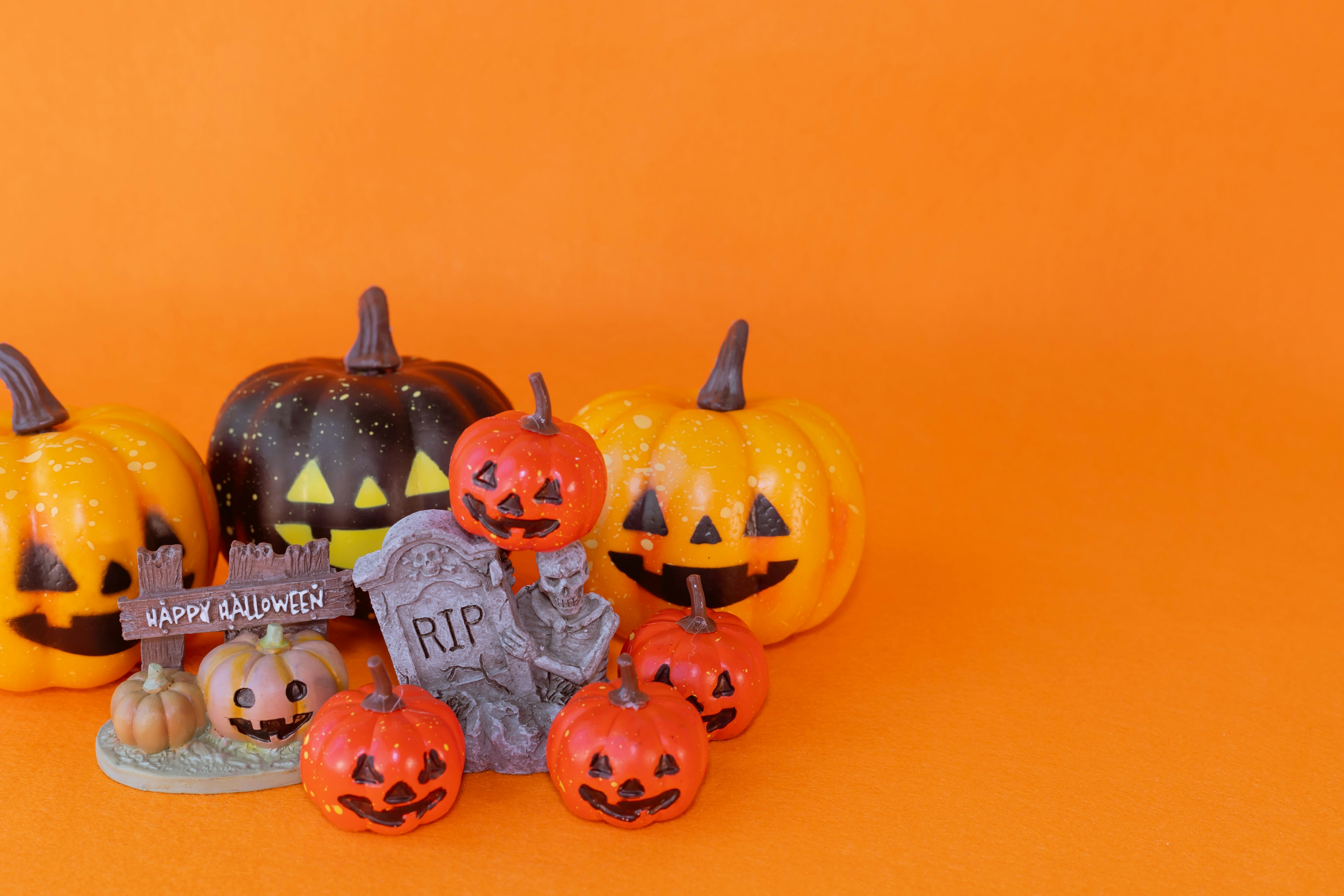 Un conjunto de decoraciones de Halloween que incluye calabazas y una lápida sobre un fondo naranja