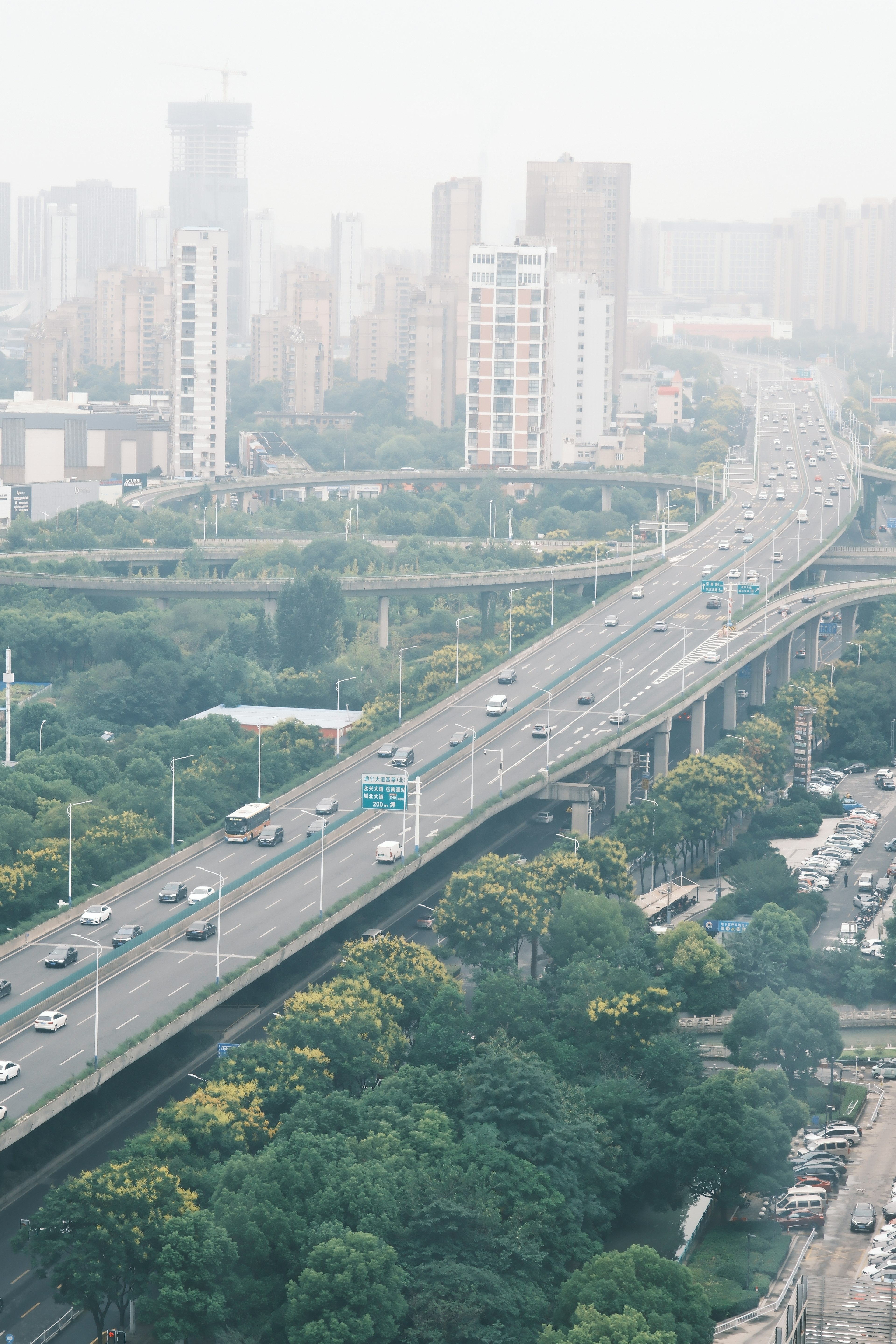 Vista aérea de una ciudad con edificios altos y un paisaje verde que incluye una carretera elevada