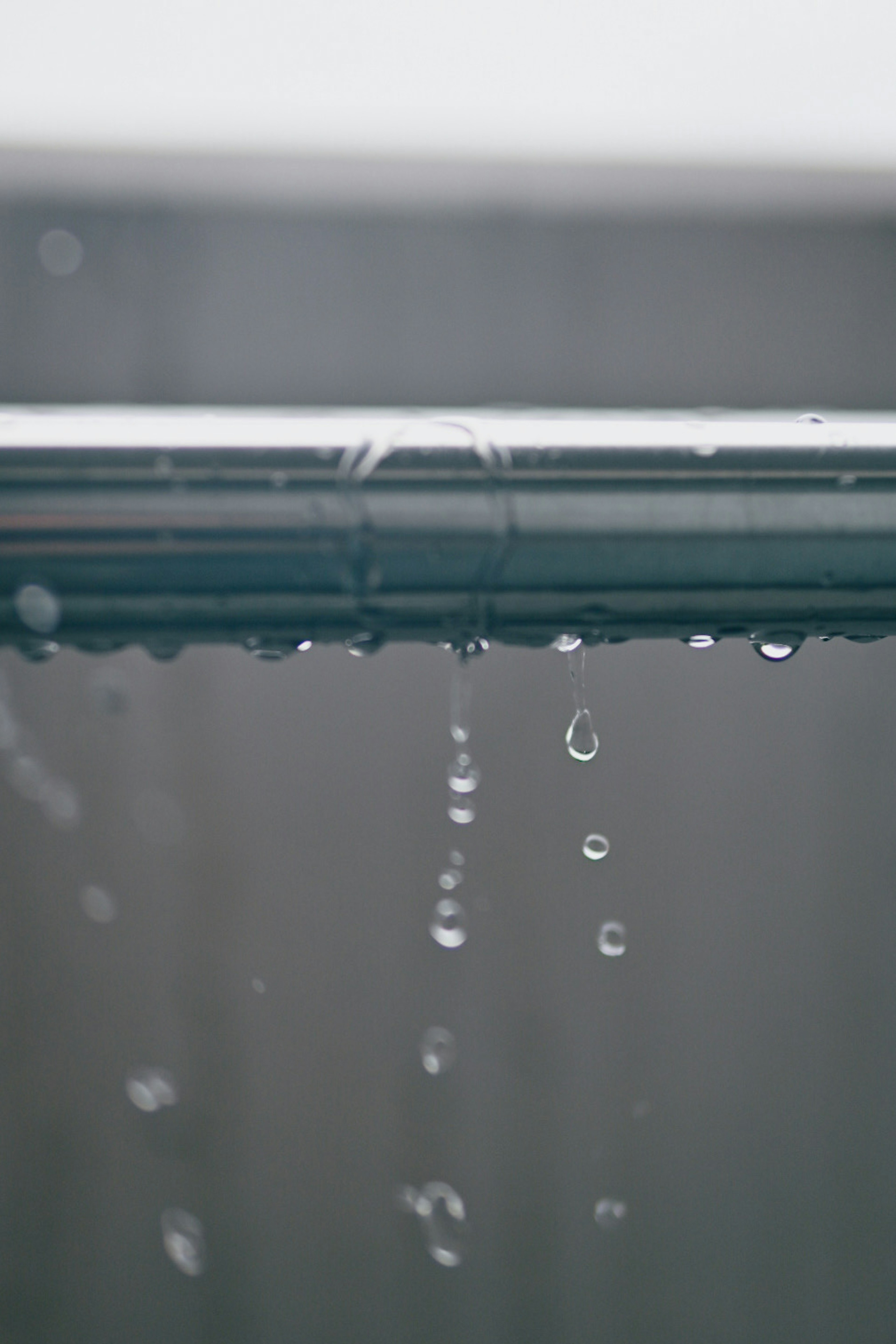 Primer plano de gotas de agua que caen de un tubo de metal