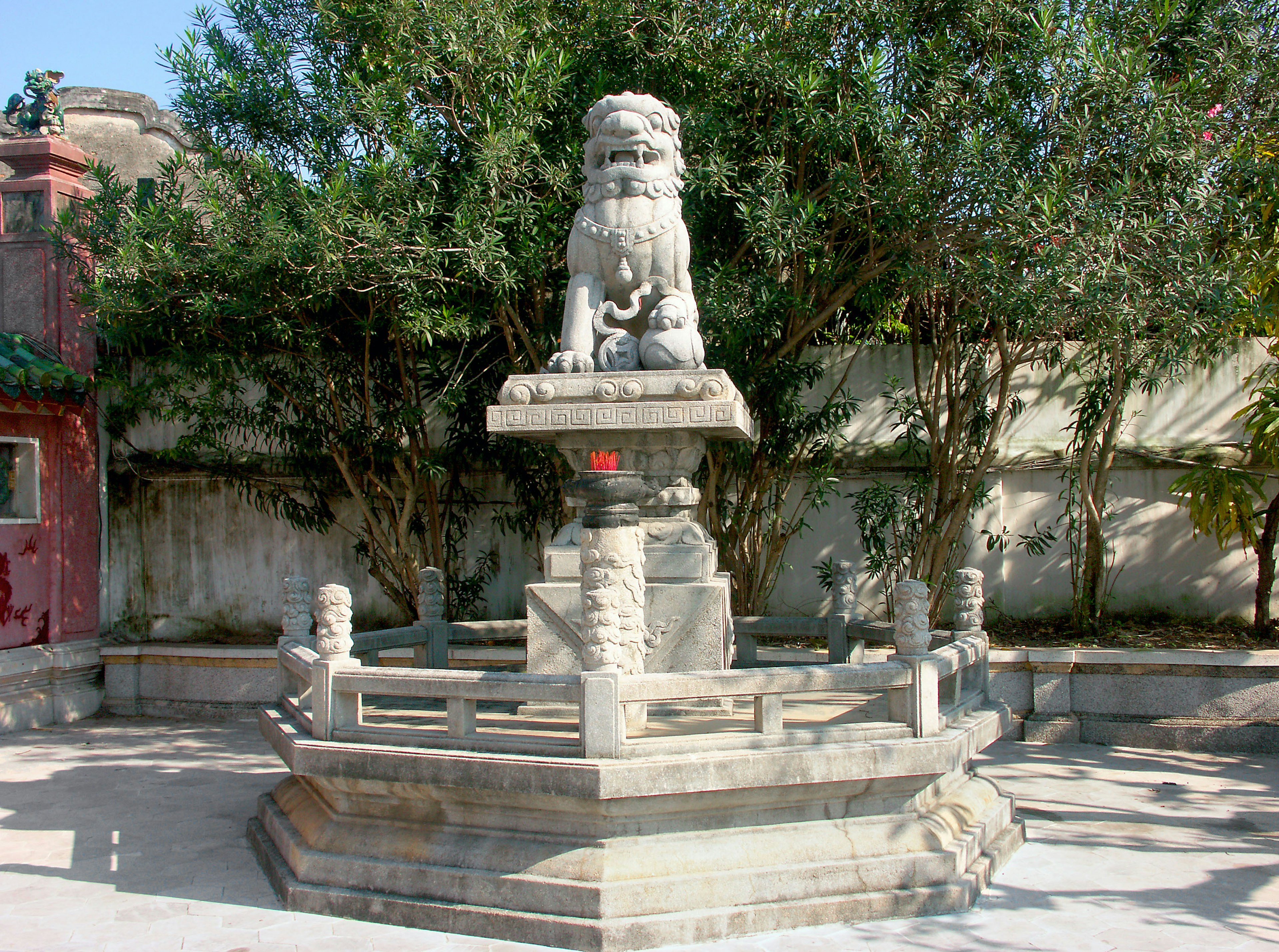 Sculpture de lion en pierre dans une fontaine de cour entourée de verdure