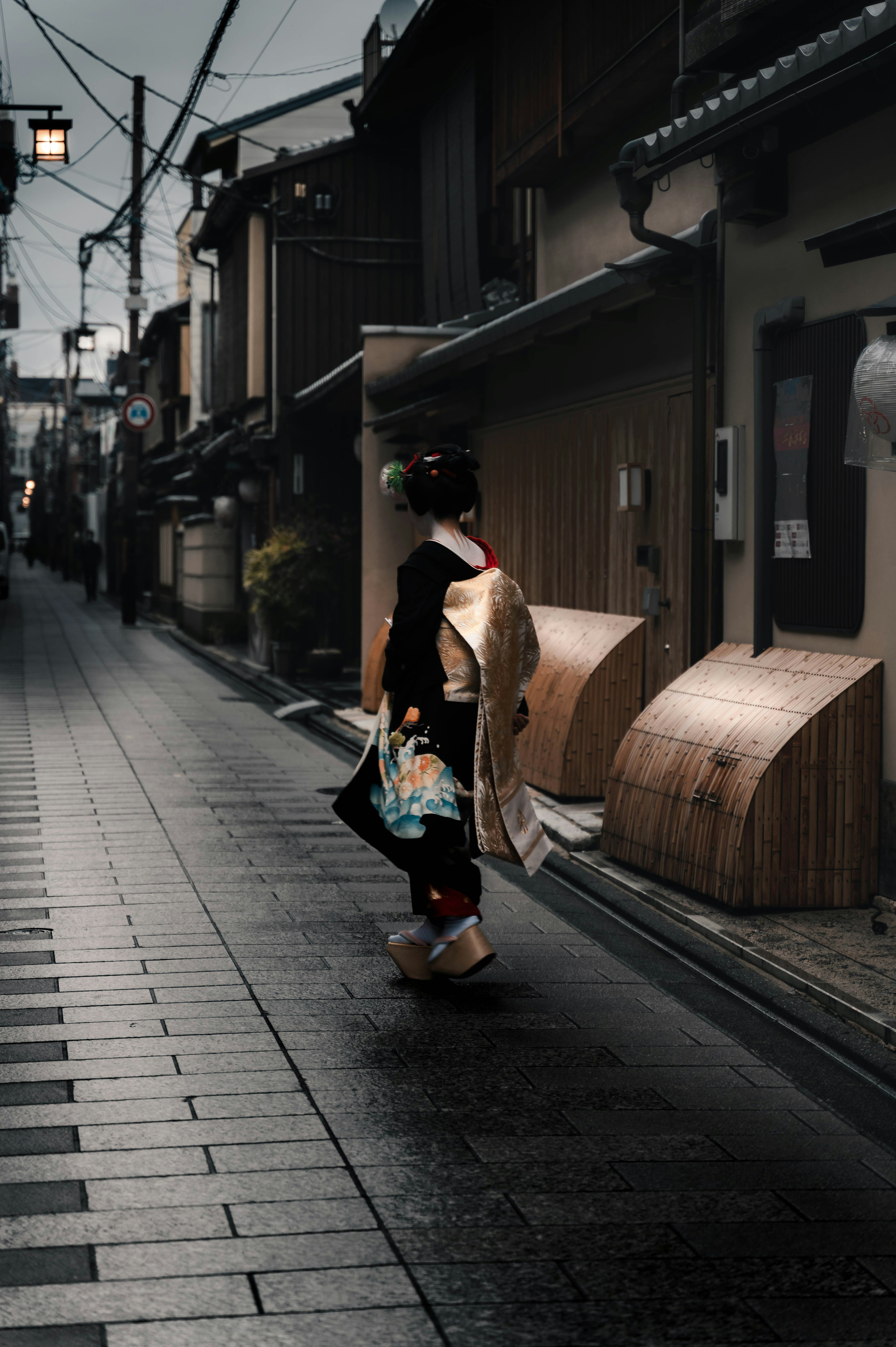 Eine Frau im Kimono, die in einer ruhigen Straße im Regen geht