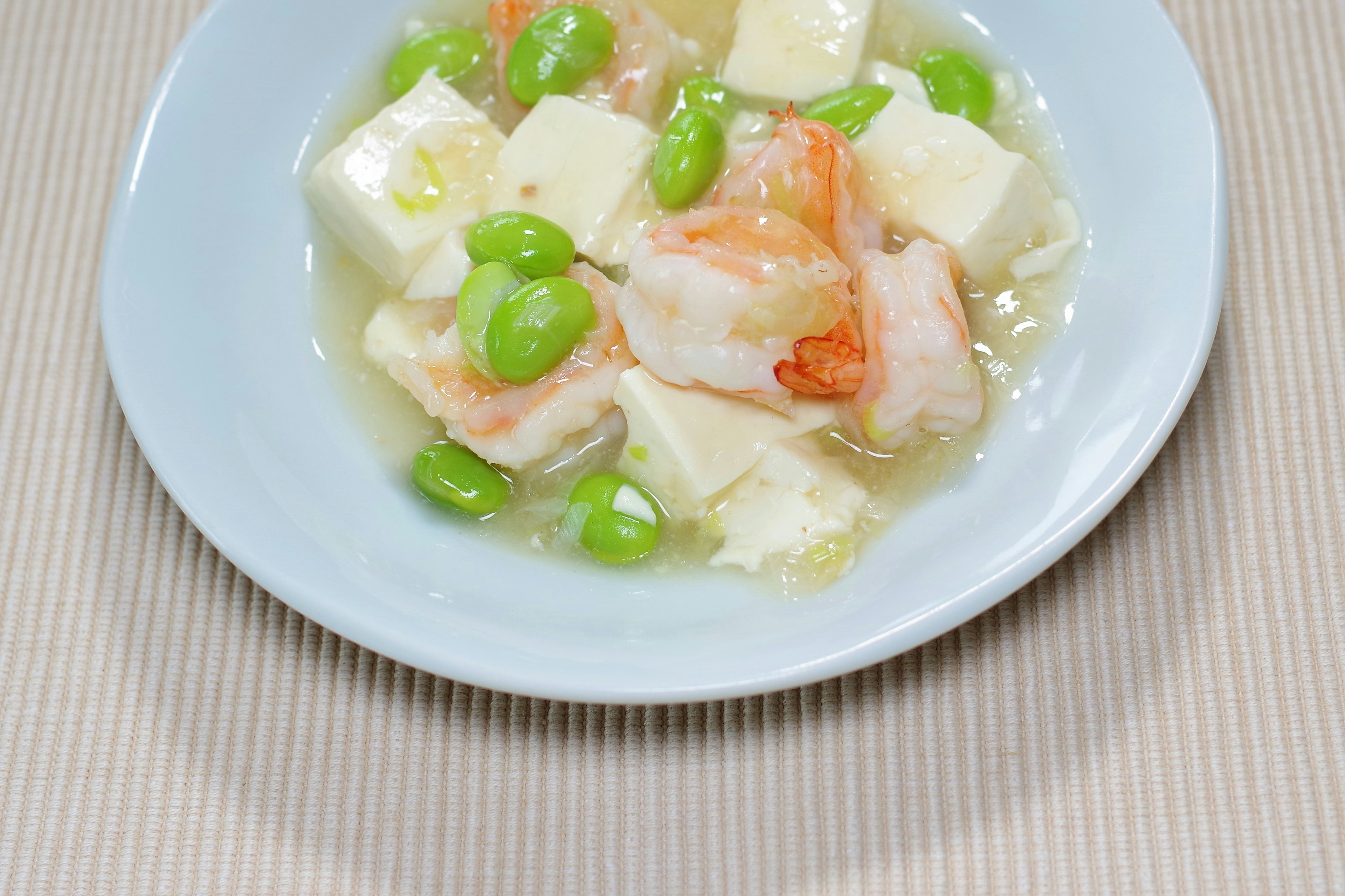 Un plato con camarones y tofu decorado con judías verdes