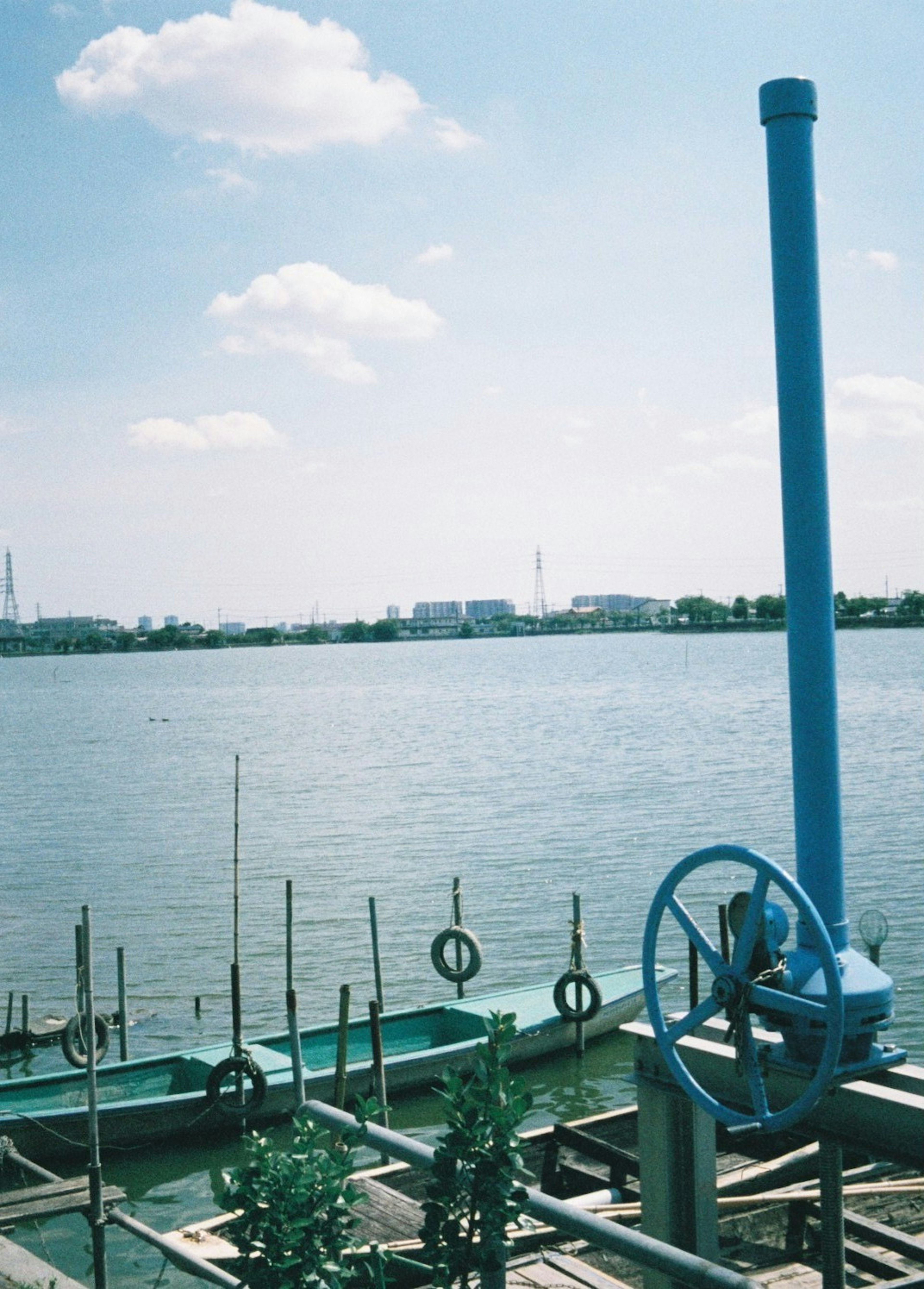 Bild von einem Flussufer mit einem blauen Rohr und ruhigem Wasser