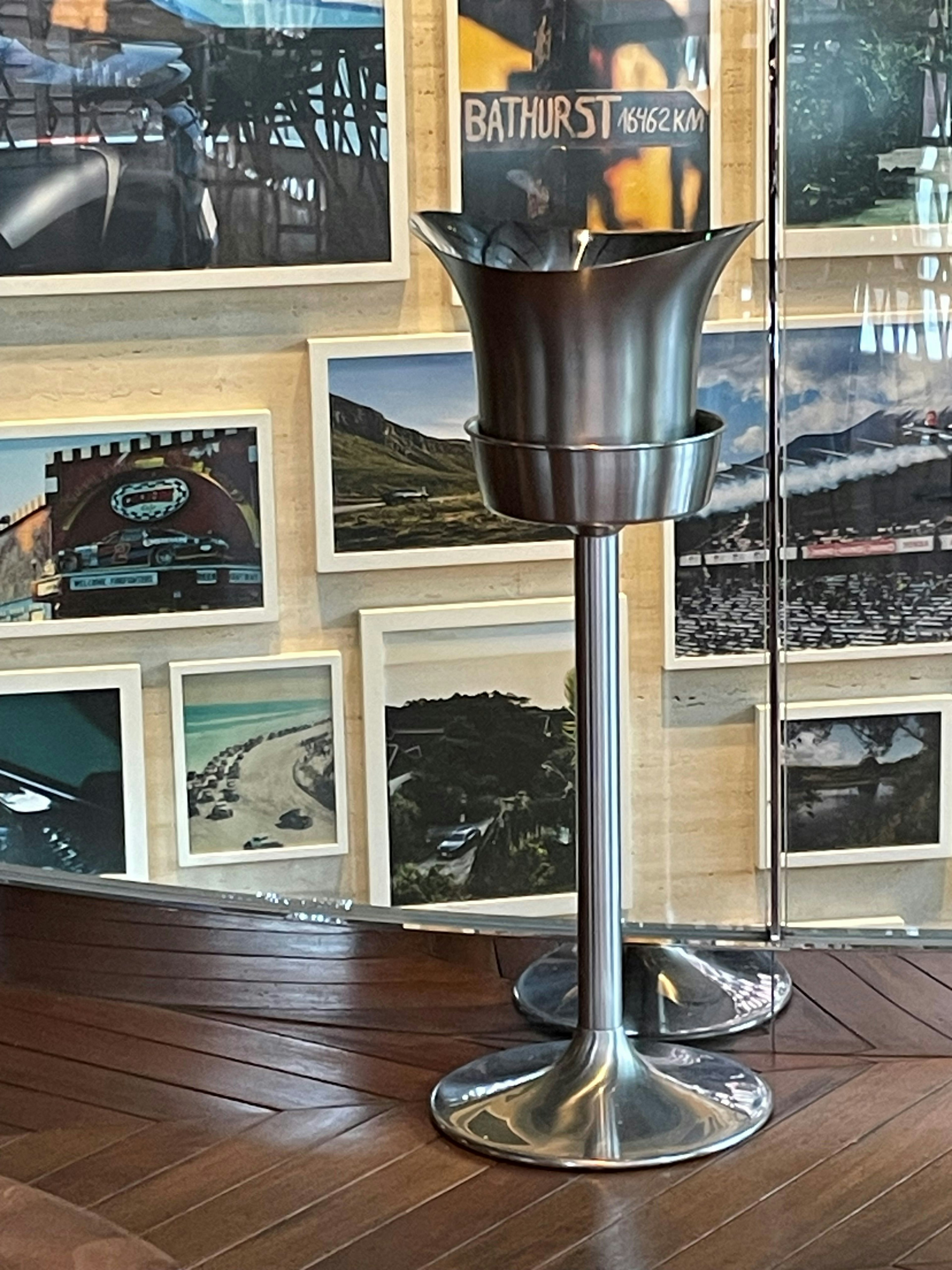 Stylish metal trash can in front of a wall of framed photographs