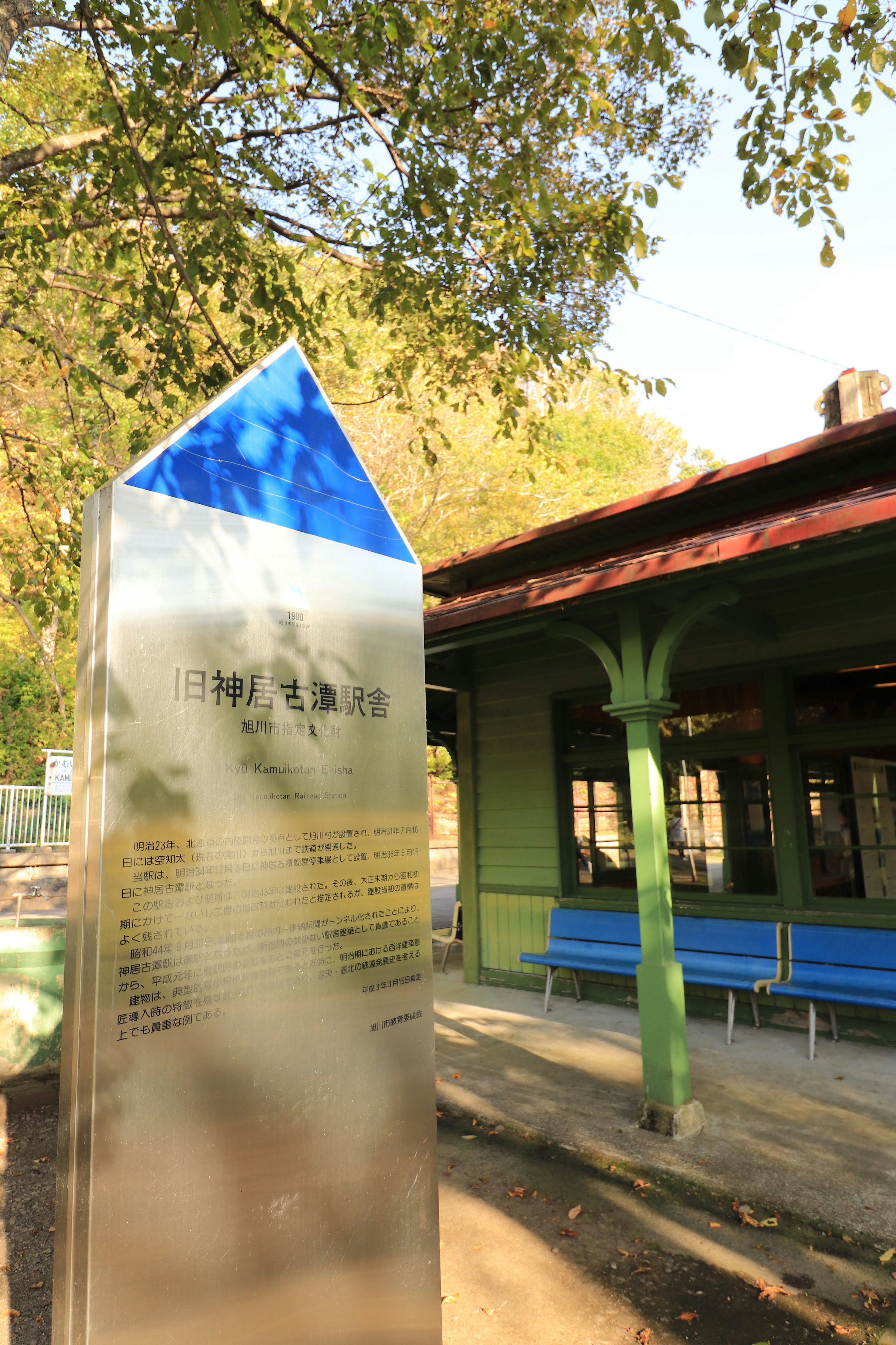 Panneau métallique avec un sommet triangulaire bleu près d'un bâtiment vert