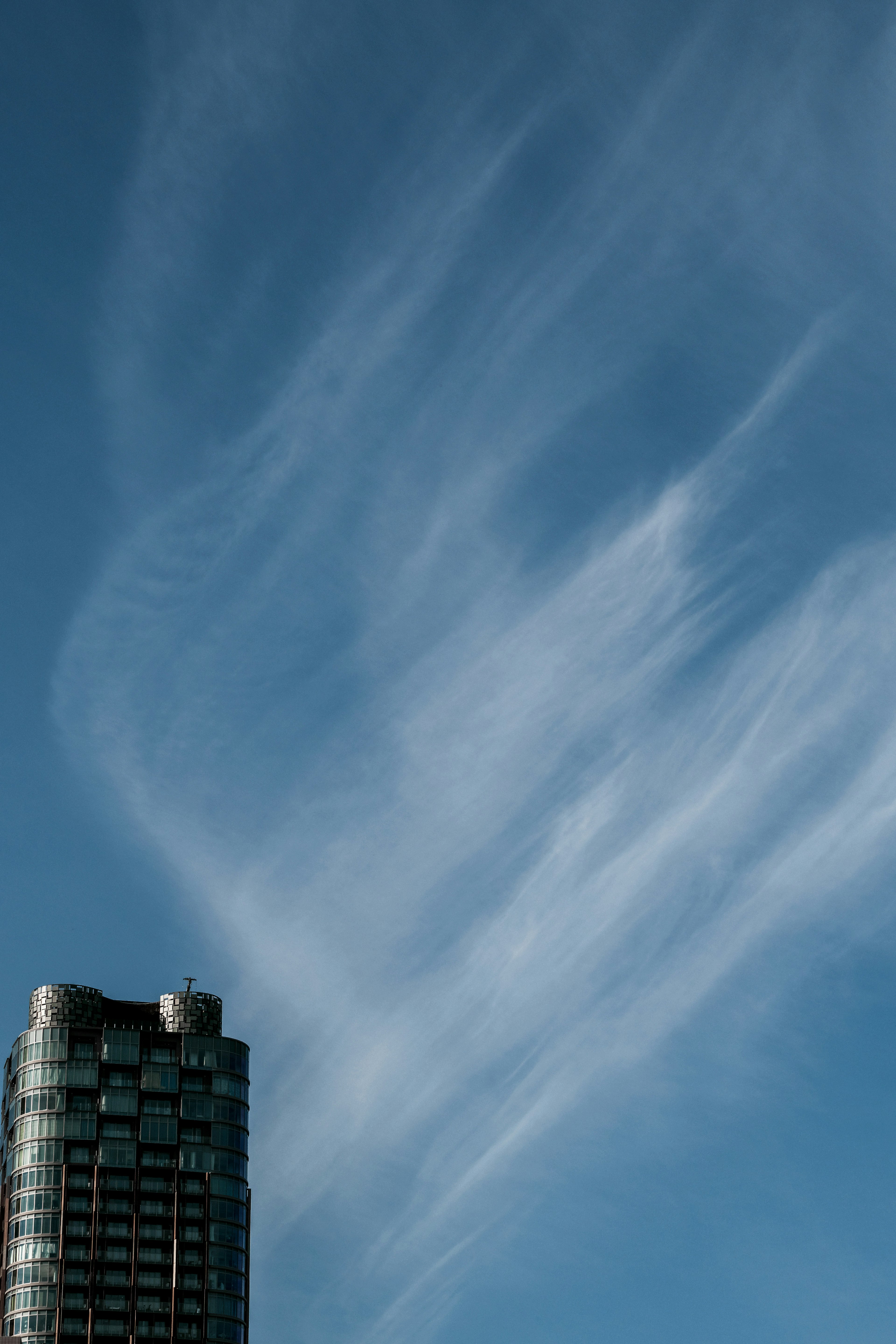 Fließende Wolken vor blauem Himmel mit einem Hochhaus