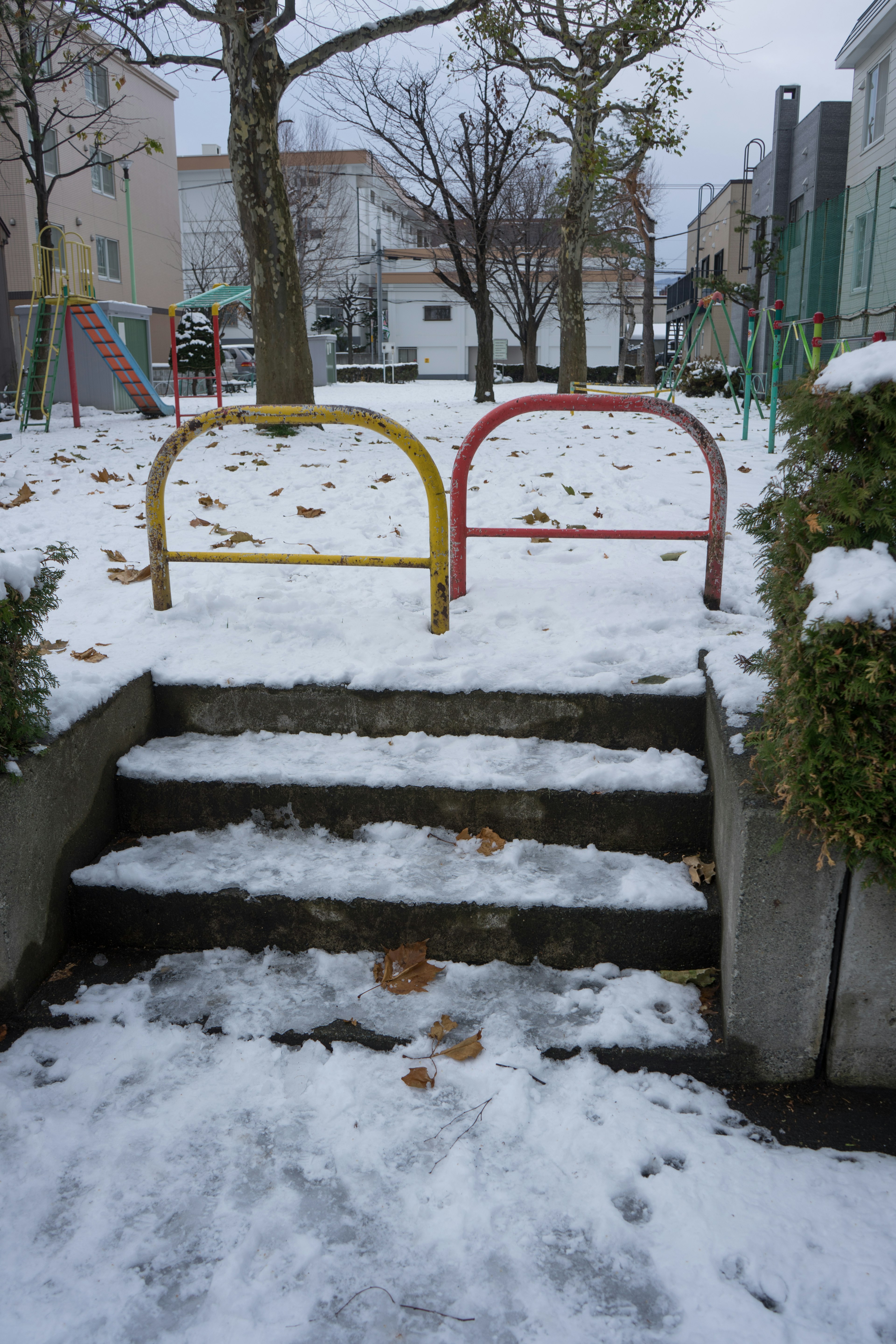 Schneebedeckte Parktreppe mit bunten Spielgeräten