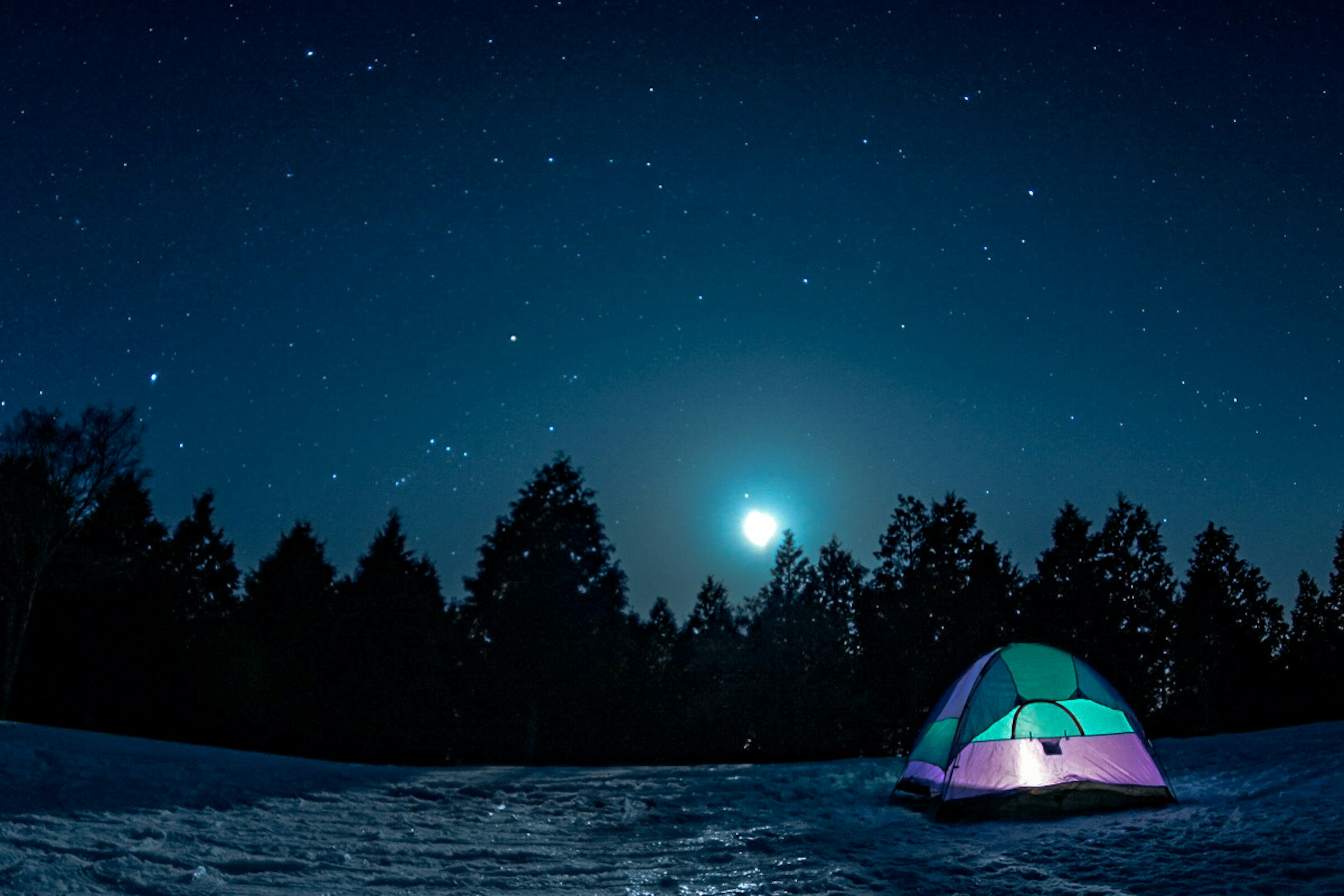 Tente colorée sous un ciel étoilé avec une lune brillante