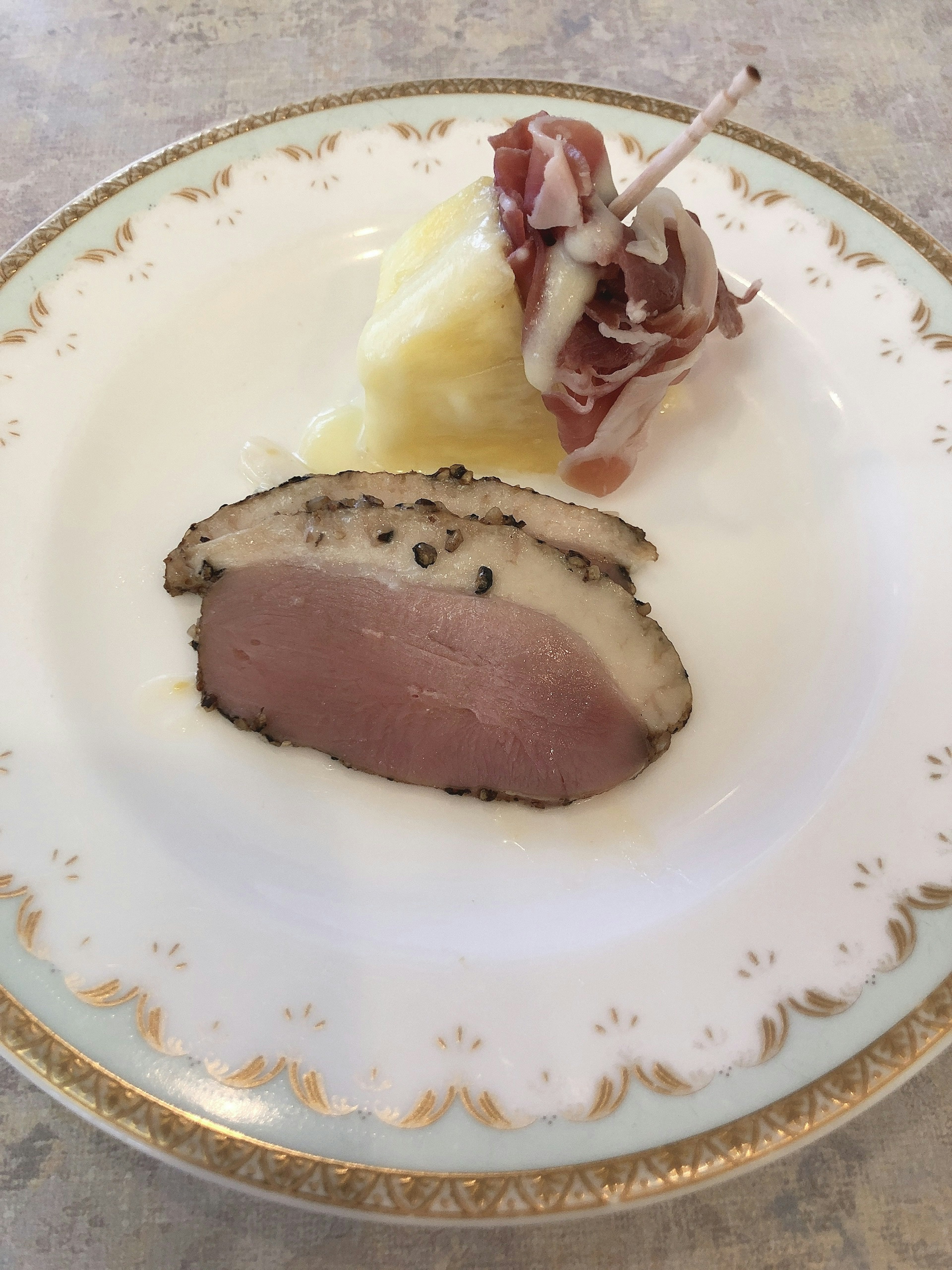 Sliced duck breast served with a portion of mashed potatoes on a white plate